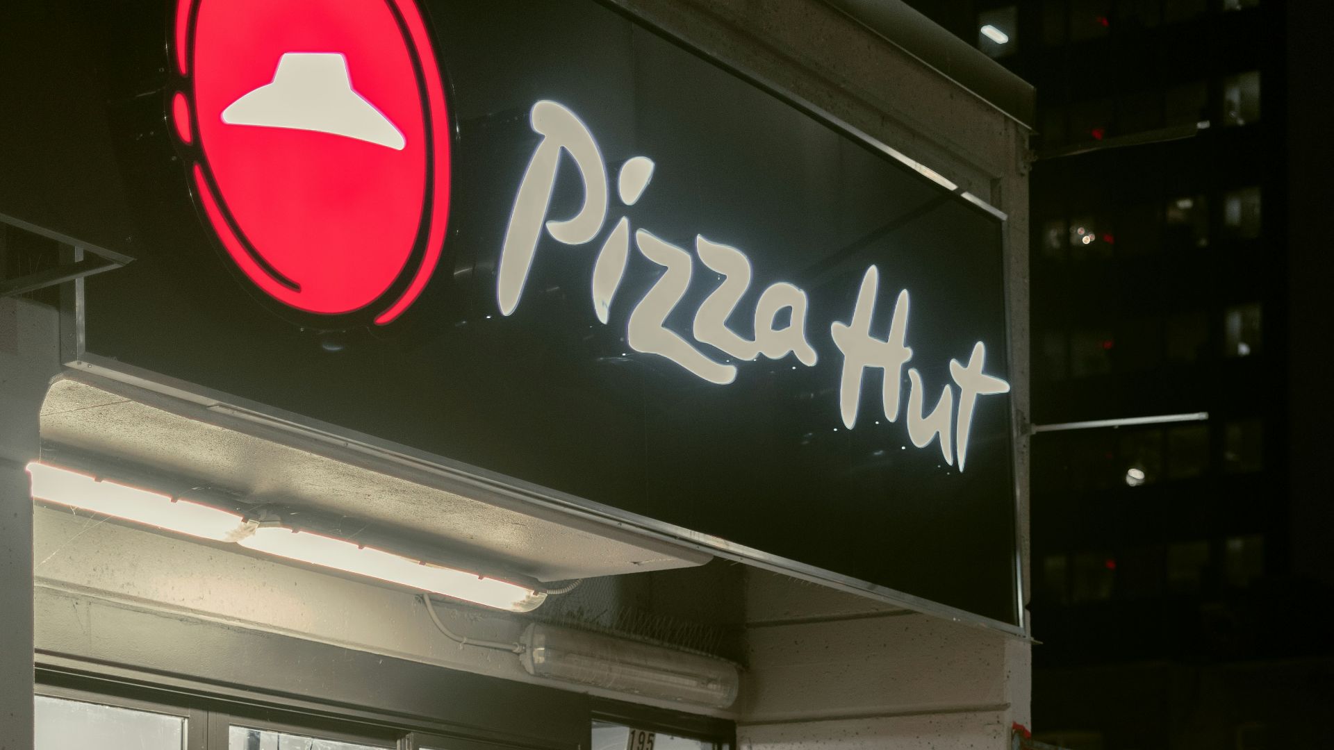 a man riding a bike past a pizza hut