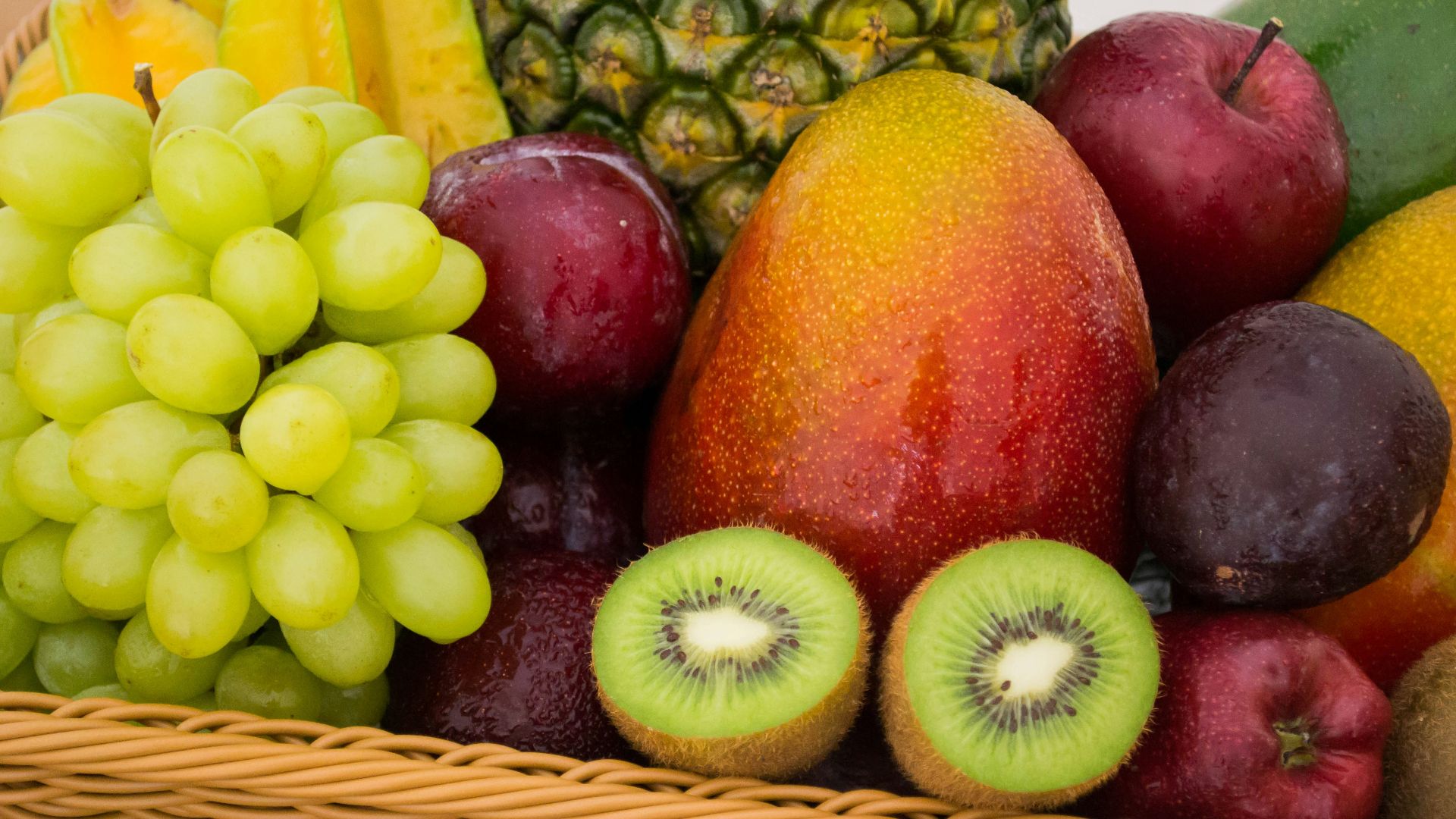red apple fruit beside green apple and yellow fruit on brown woven basket