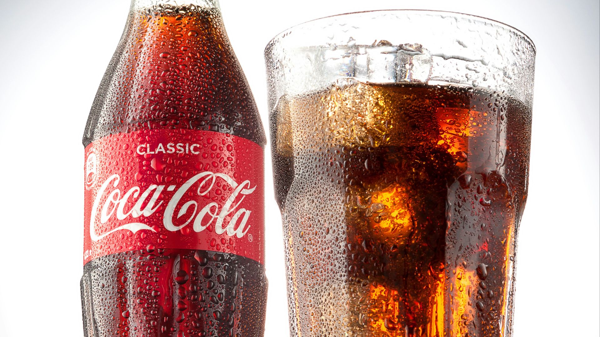 coca cola bottle beside drinking glass