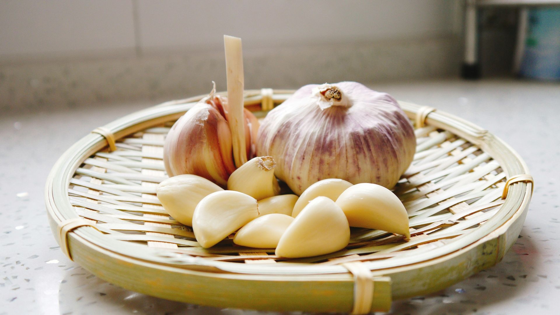 a basket of garlic and garlic bulbs on a counter