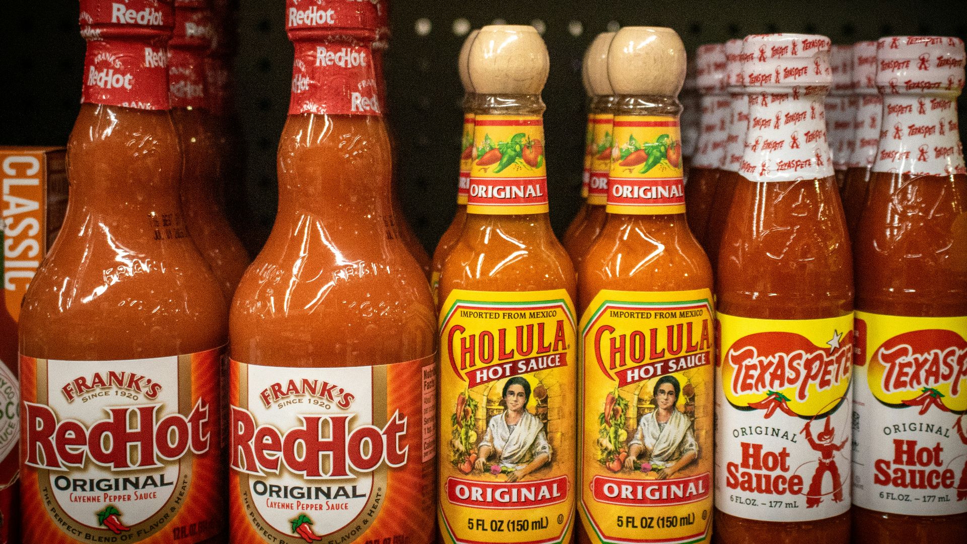 Hot sauce bottles line a store shelf.