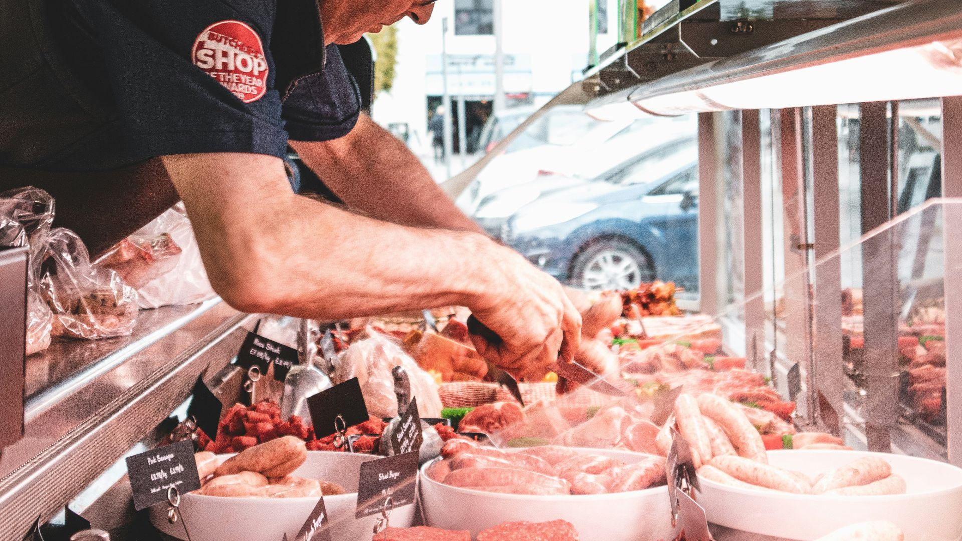 man in black crew neck t-shirt and black hat standing in front of raw meat