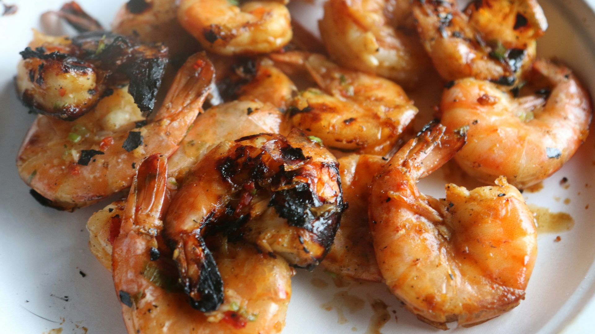 A white plate topped with grilled shrimp and broccoli