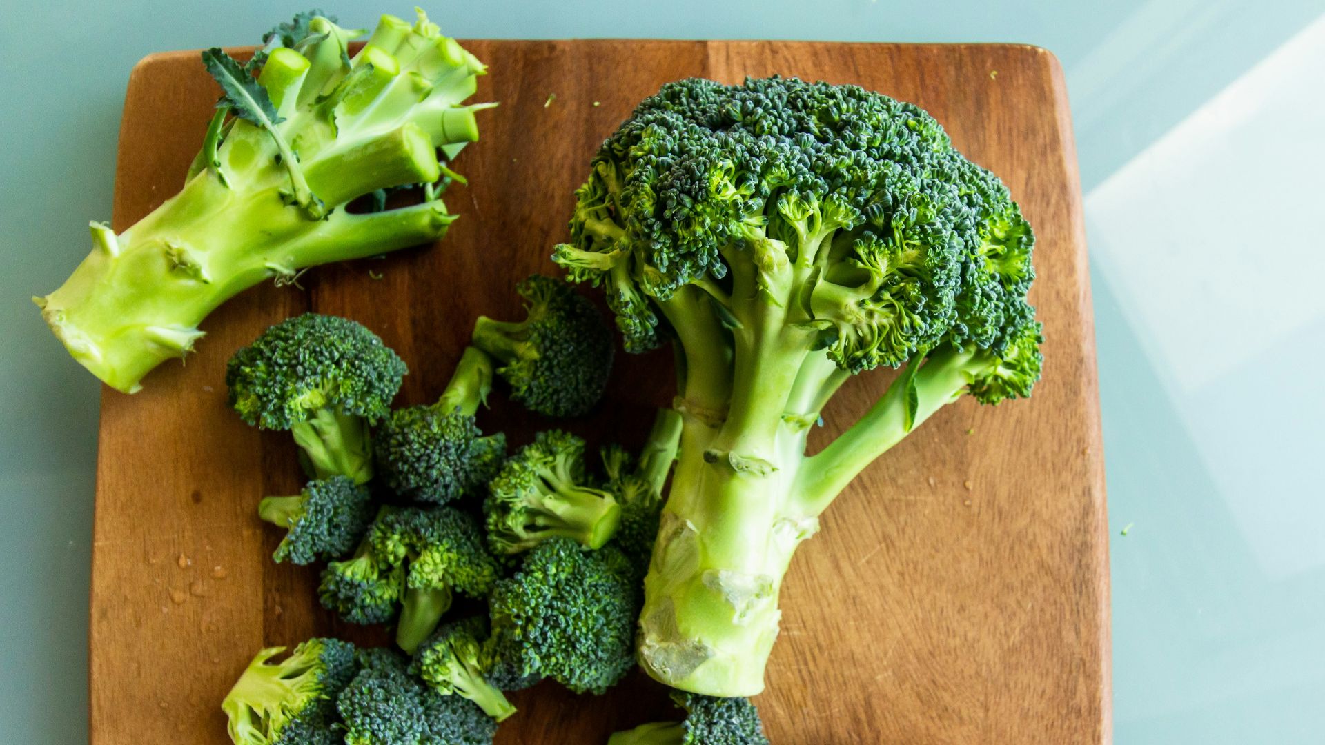 broccoli on brown wooden chopping board