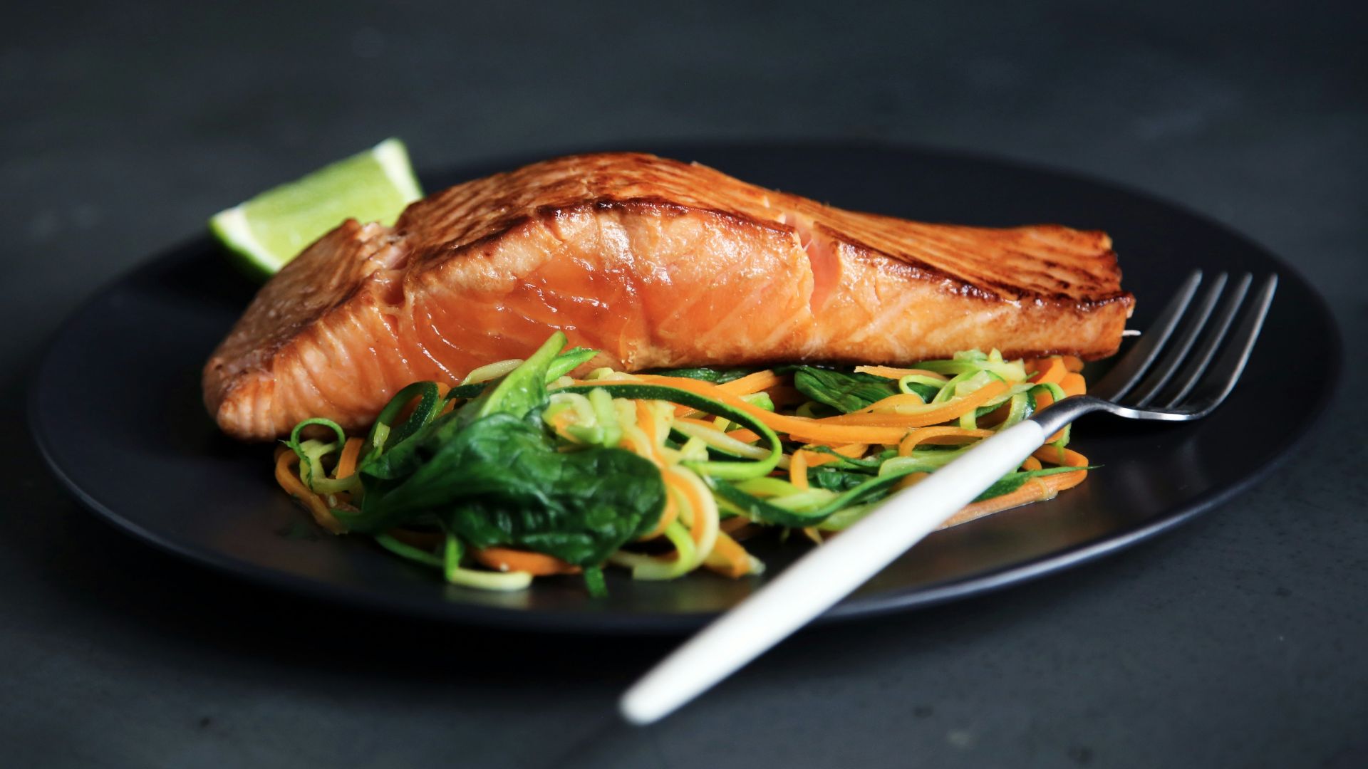 grilled fish, cooked vegetables, and fork on plate