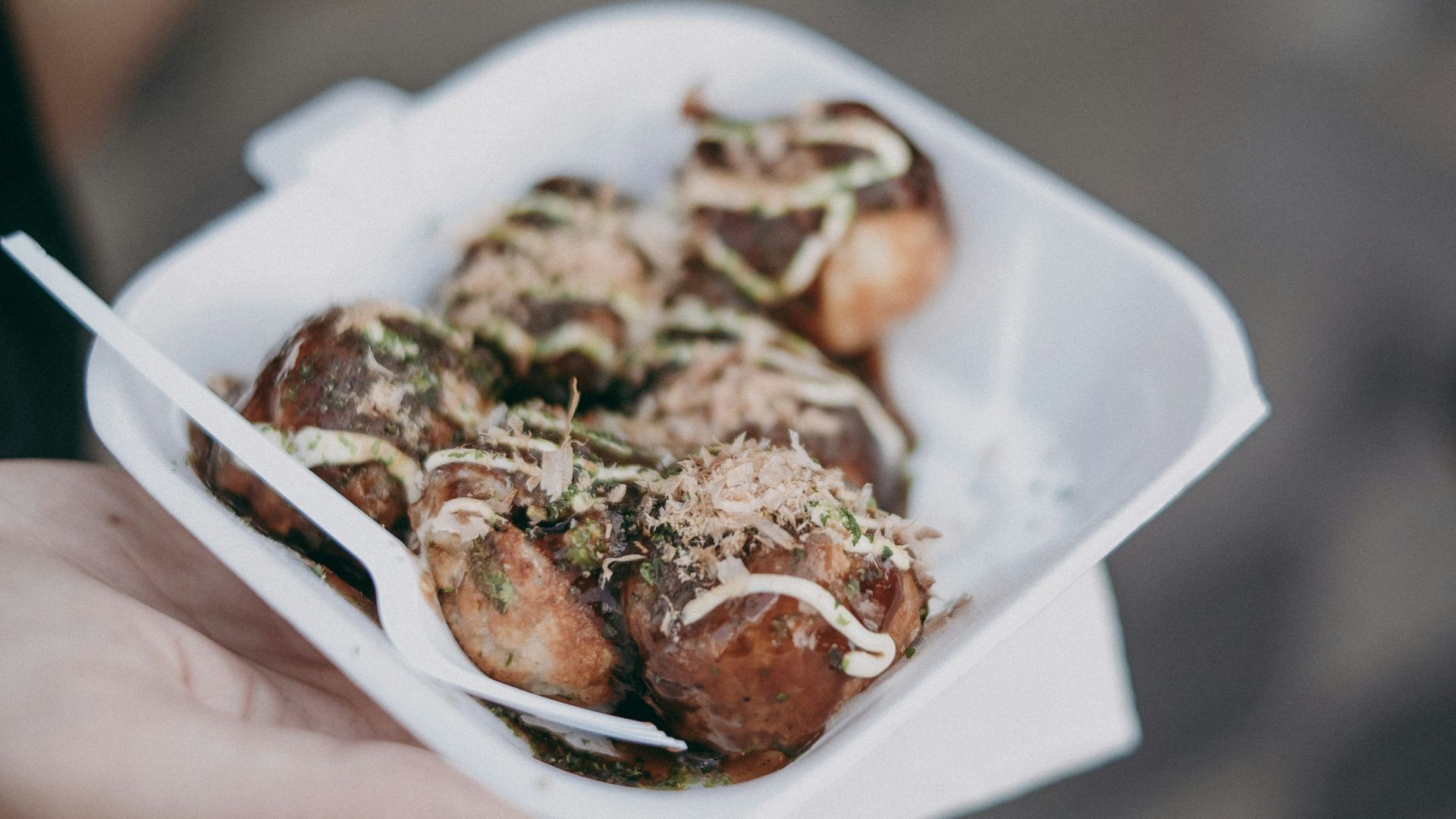 a person holding a paper container filled with food