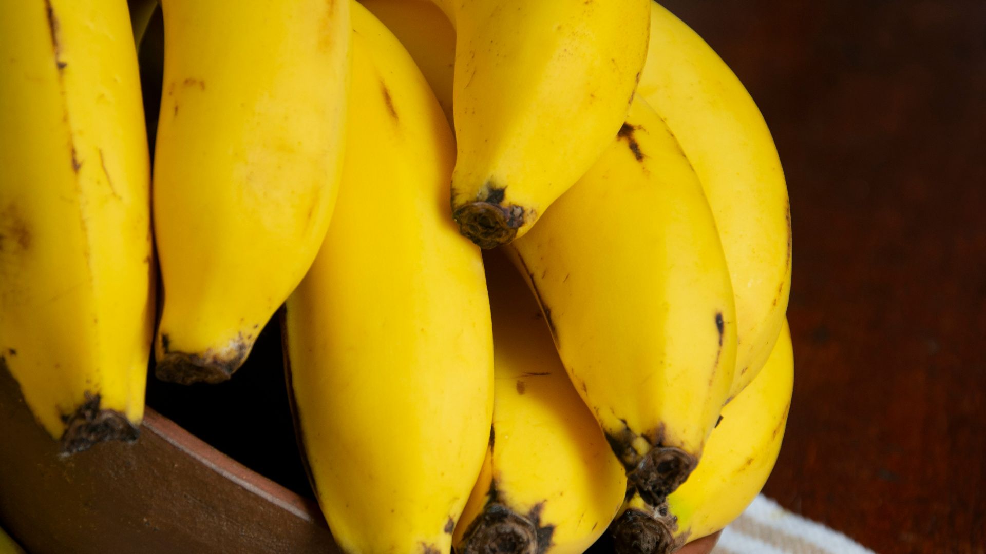 yellow banana fruit on brown wooden bowl