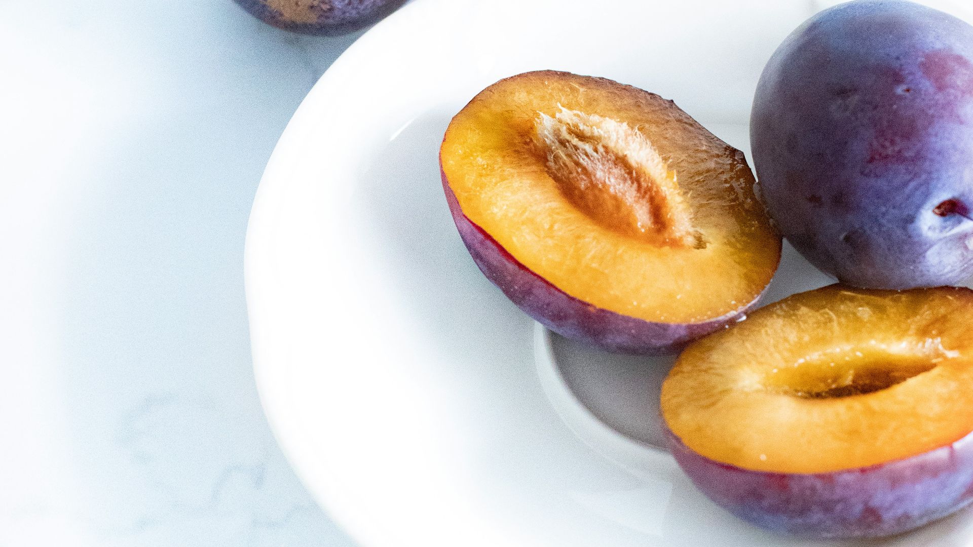 purple and yellow round fruits on white ceramic plate