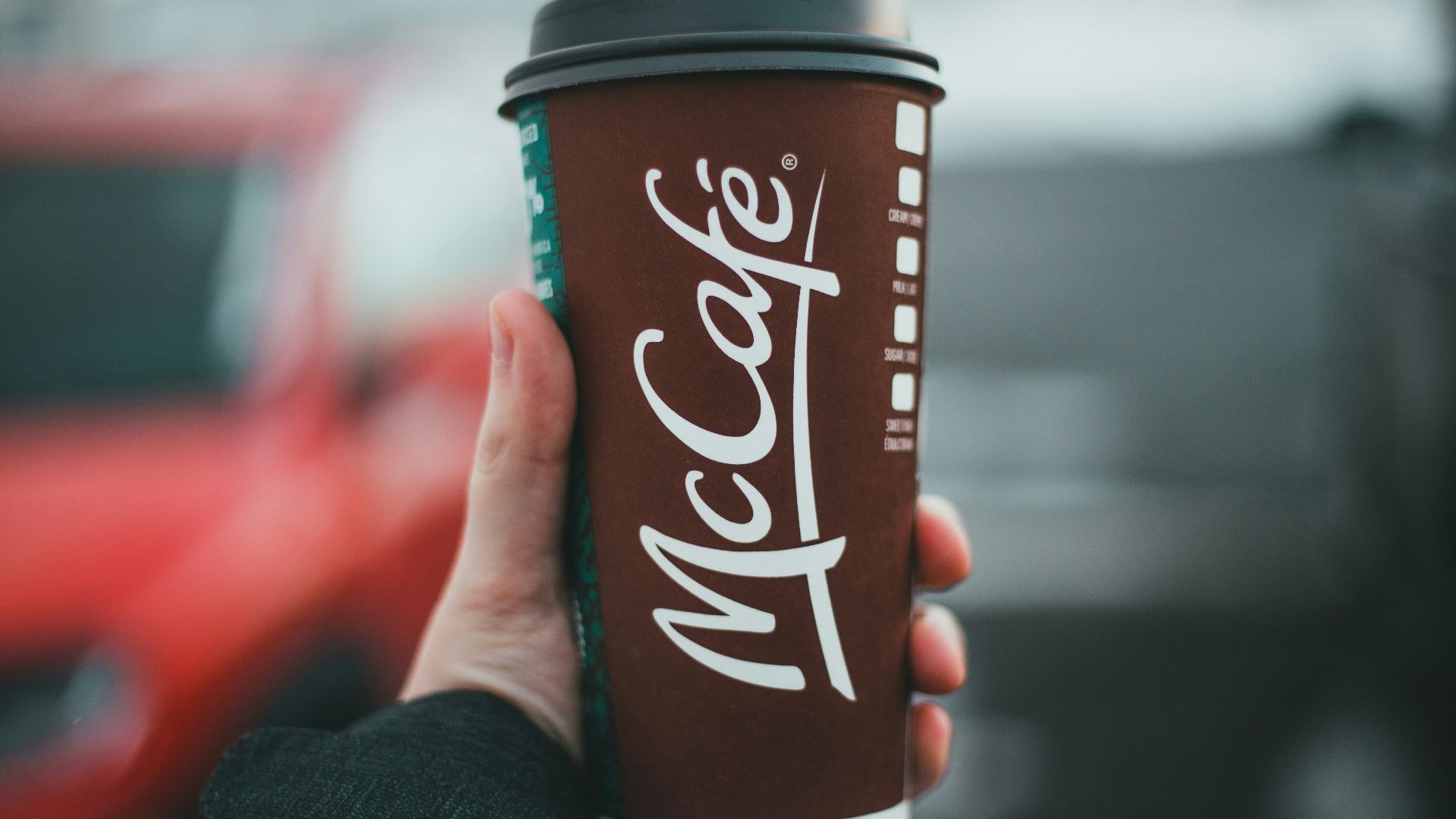 person holding red and white coca cola disposable cup