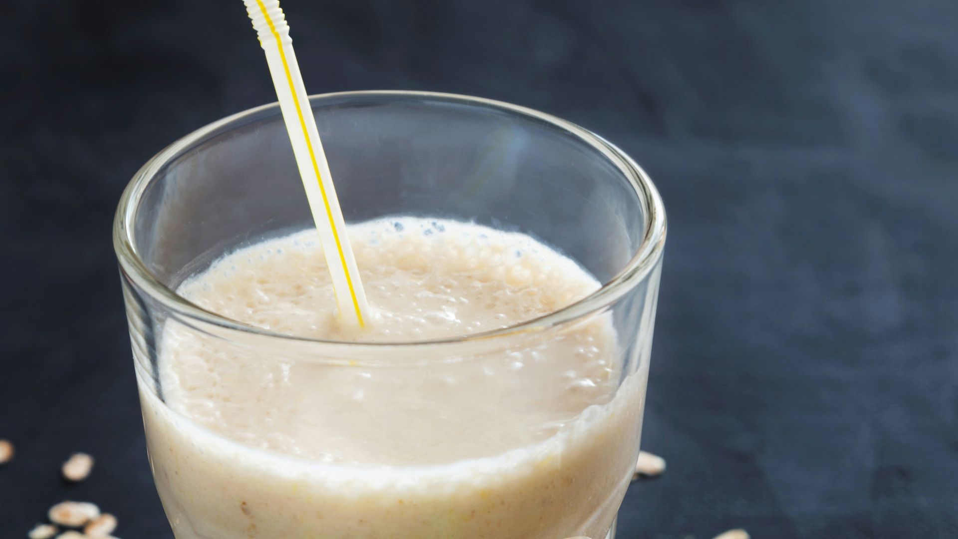 a banana smoothie in a glass next to a plate of sliced bananas