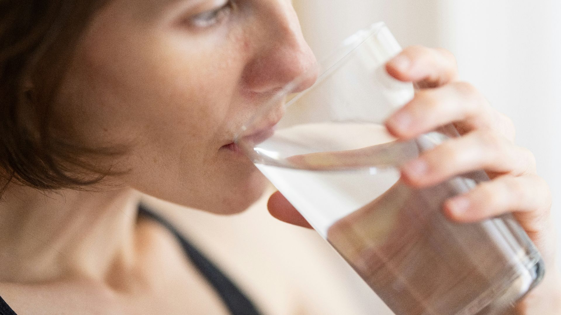 woman in black tank top drinking water