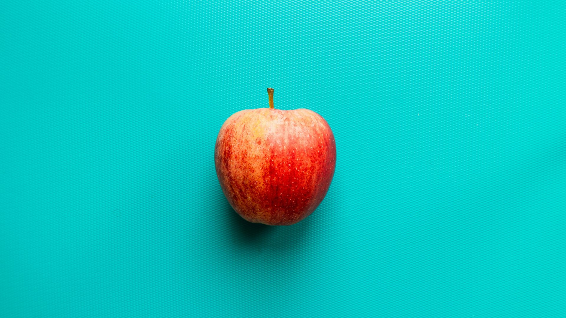 red apple fruit on blue surface