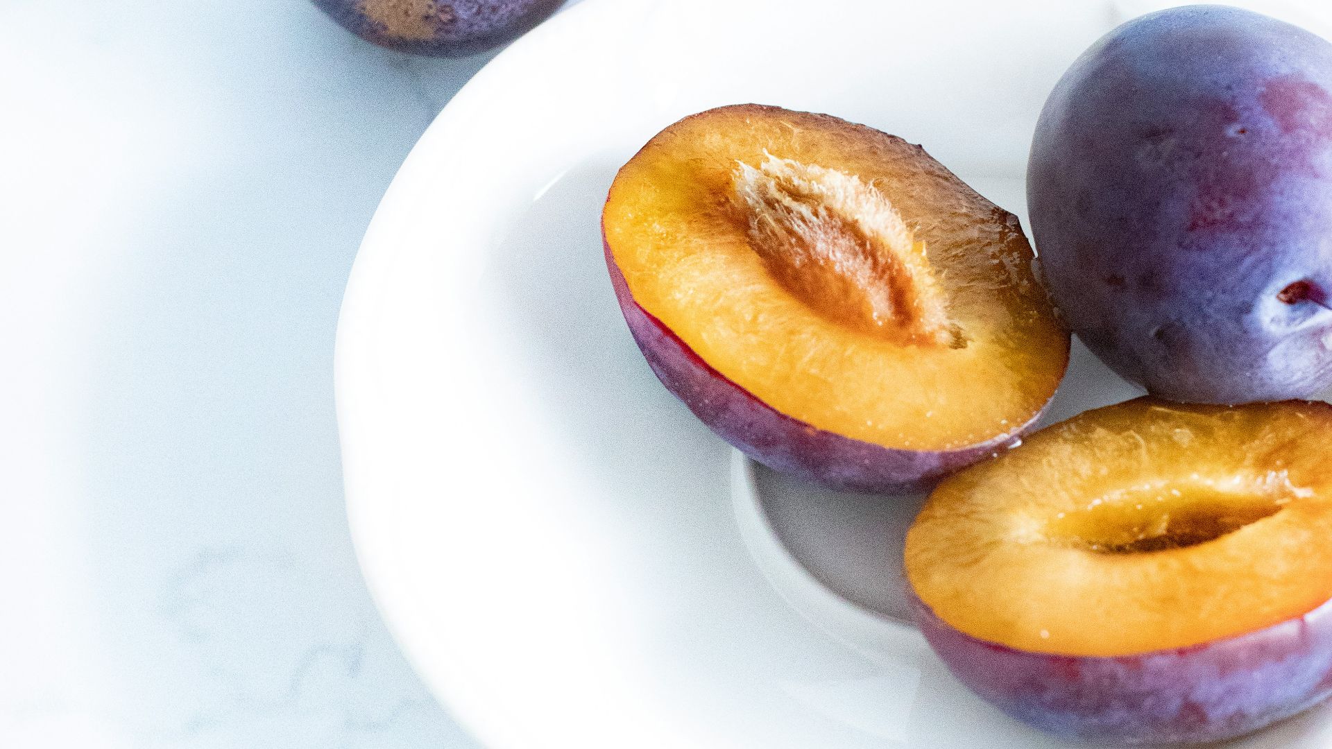 purple and yellow round fruits on white ceramic plate