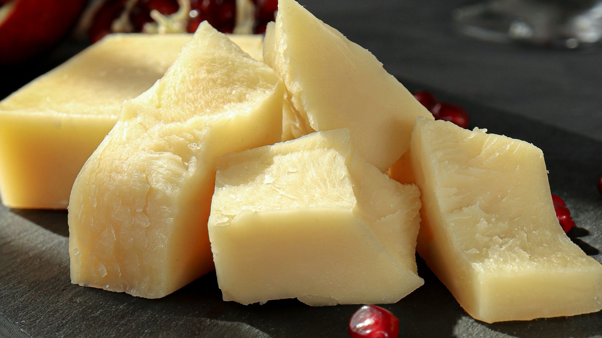 sliced cheese on black plate beside wine glass