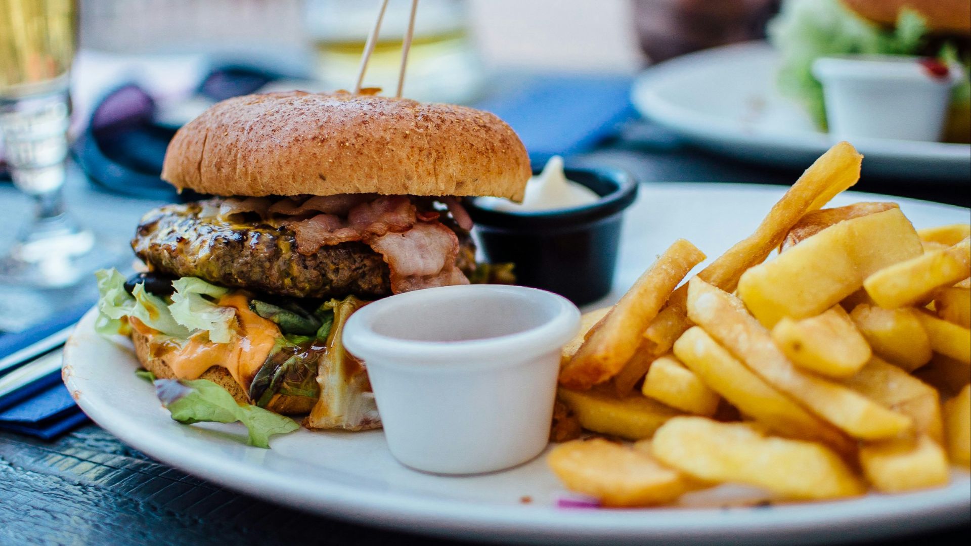 selective focus photography of burger patty, mayonnaise, and French fries served on platter