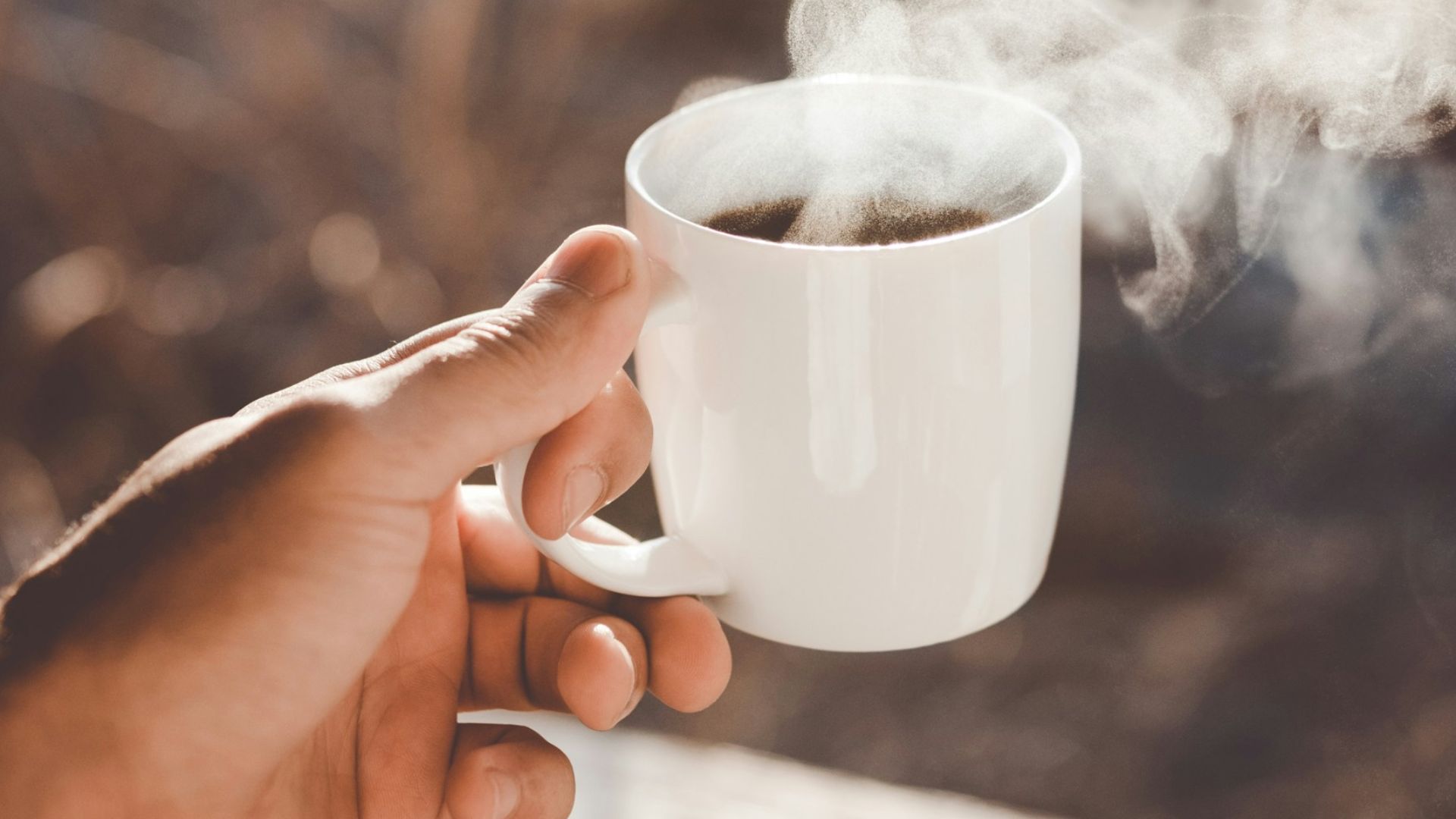 person holding white ceramic cup with hot coffee