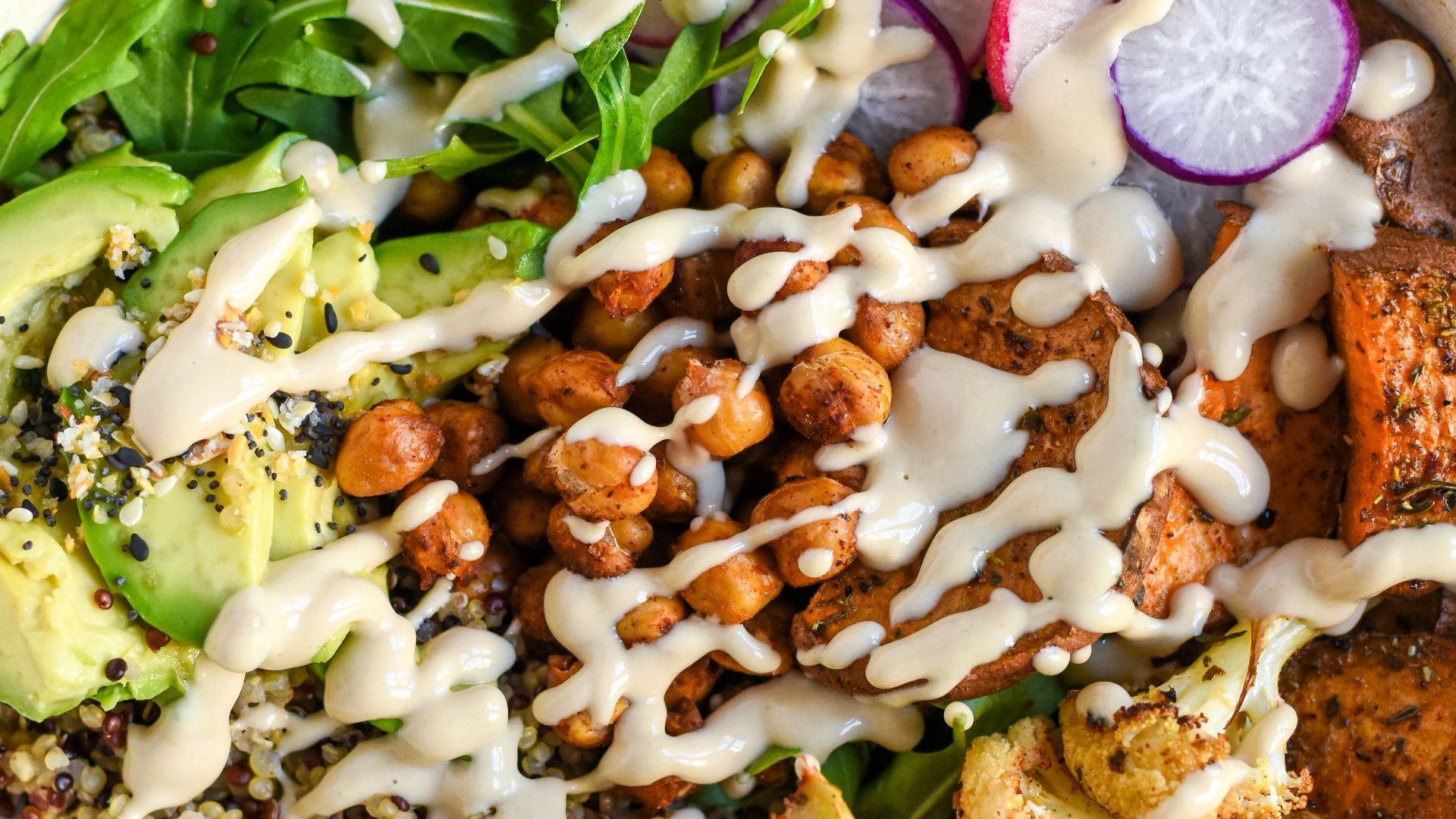 a bowl filled with vegetables and dressing next to a glass of milk