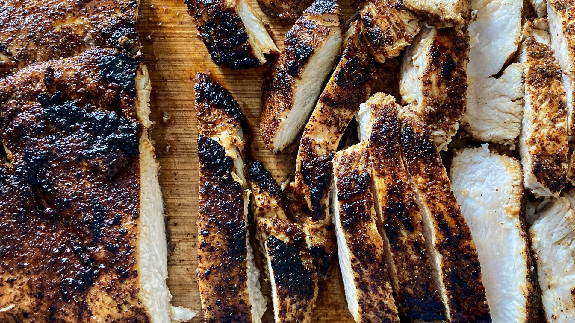 a wooden cutting board topped with sliced up meat