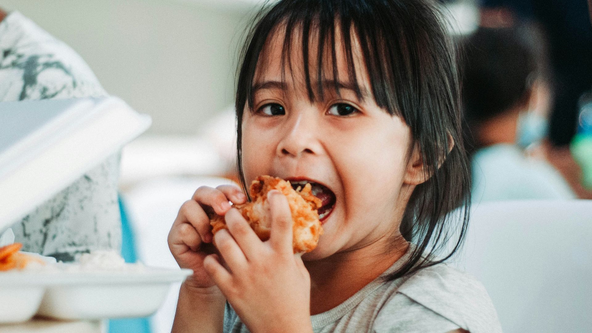 girl biting a good by table at daytime