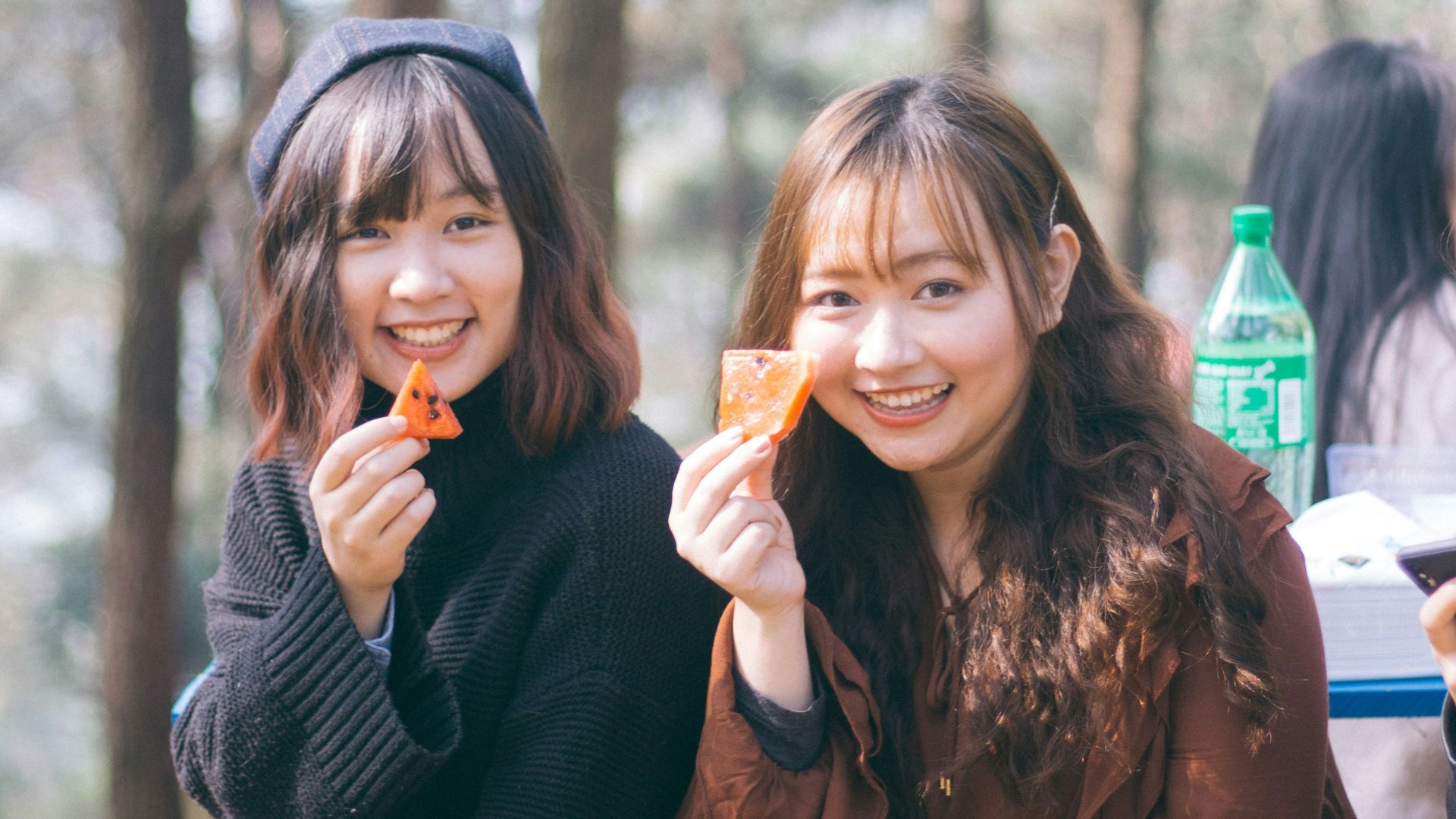 two women holding potato chips while sitting and smiling