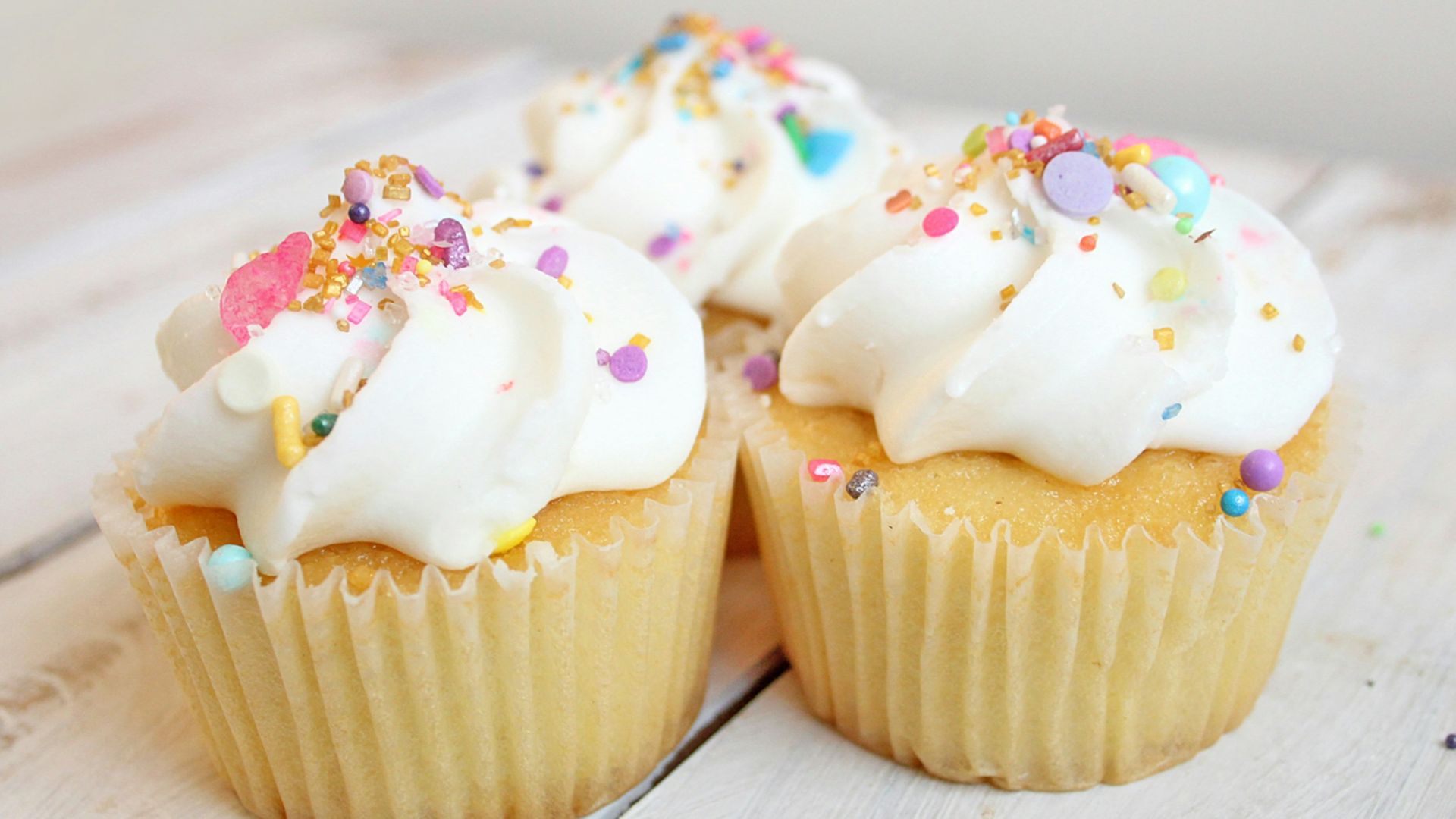 three cupcakes on white wood