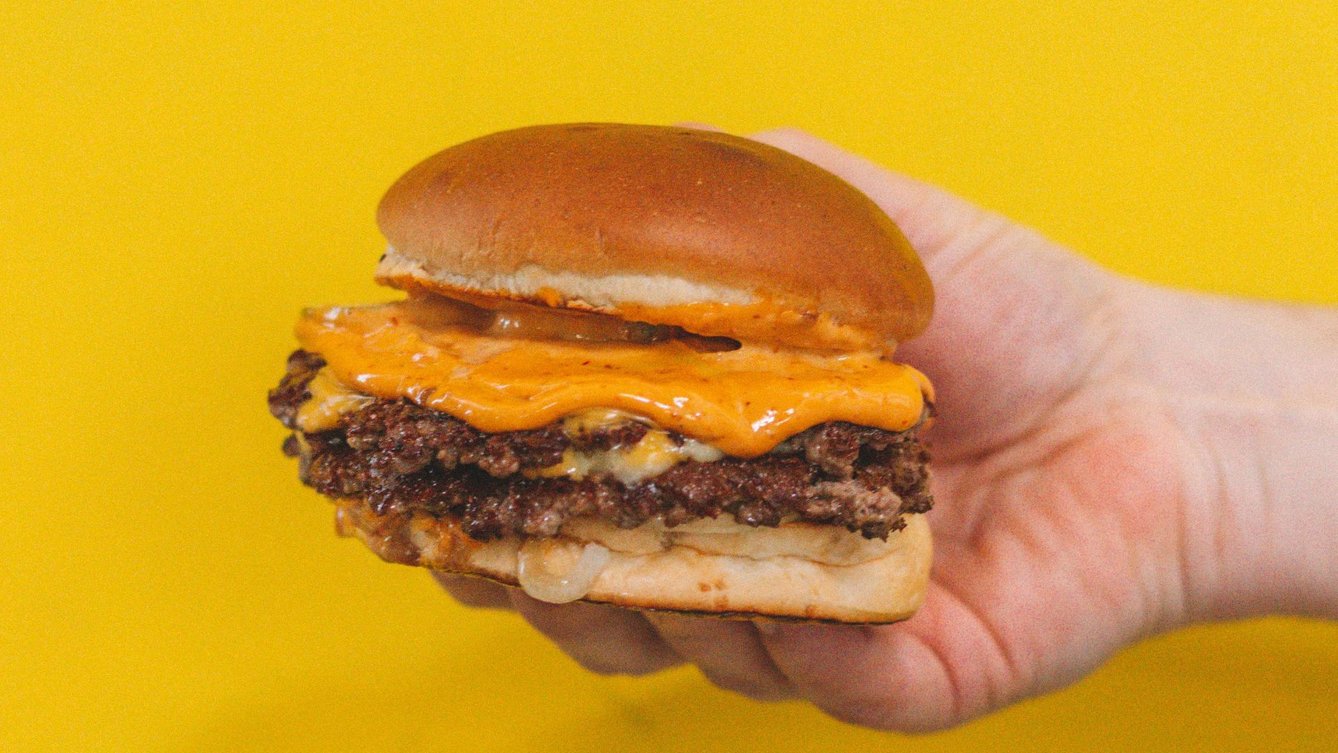 person holding burger with patty
