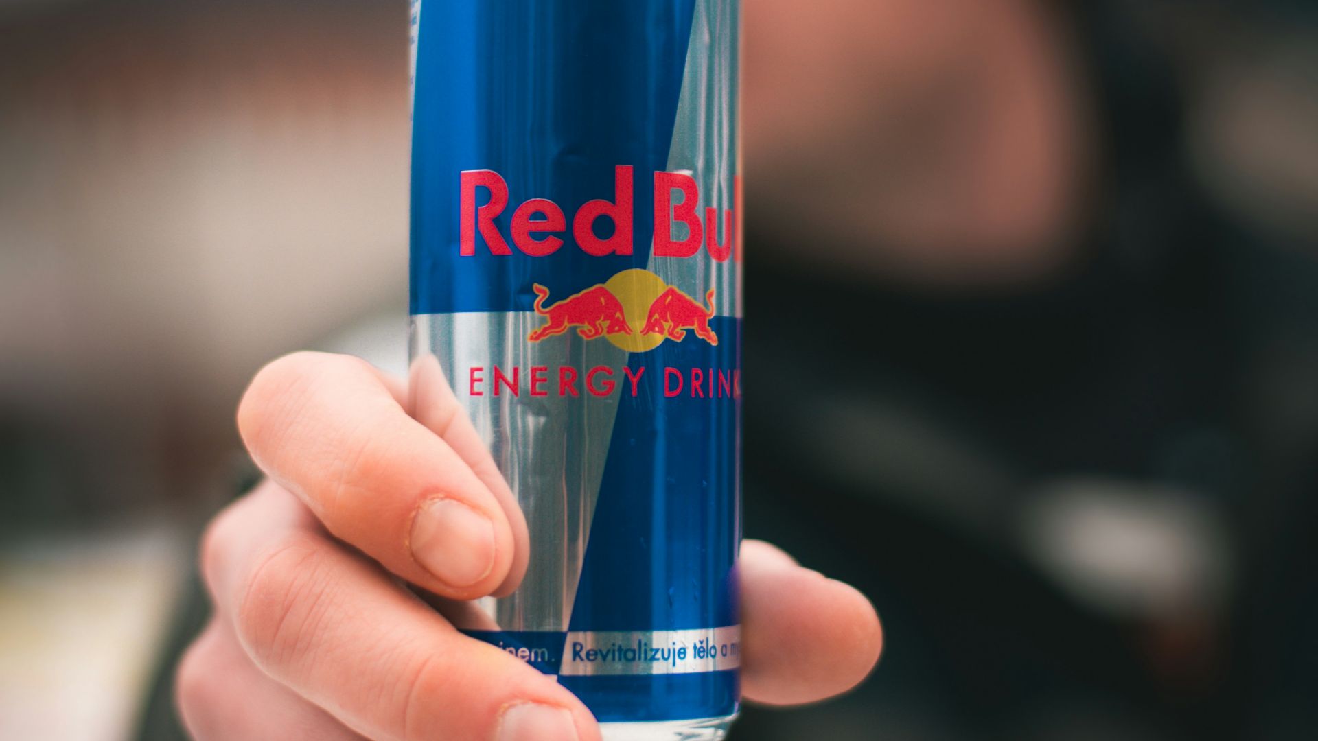 person holding red bull energy drink can