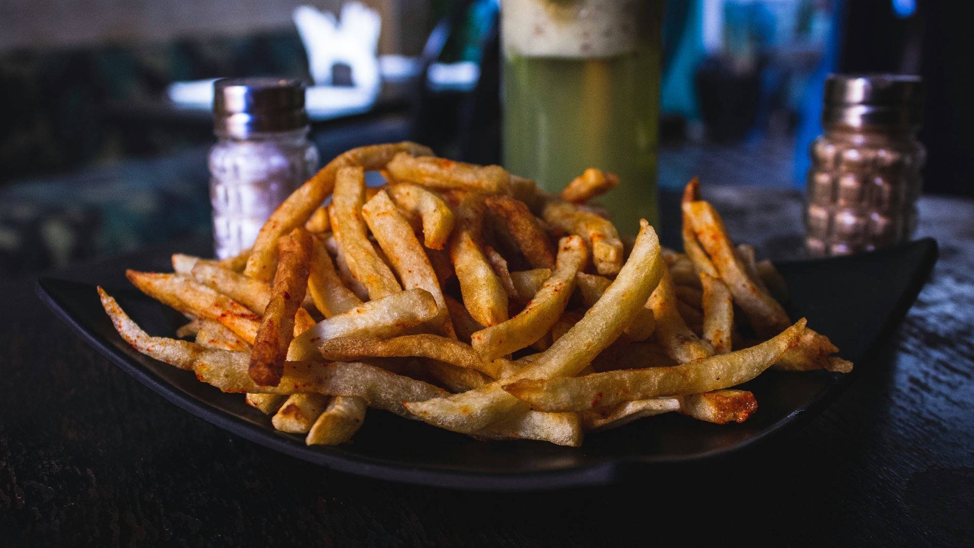 potato fries on black ceramic plate on top of wooden table