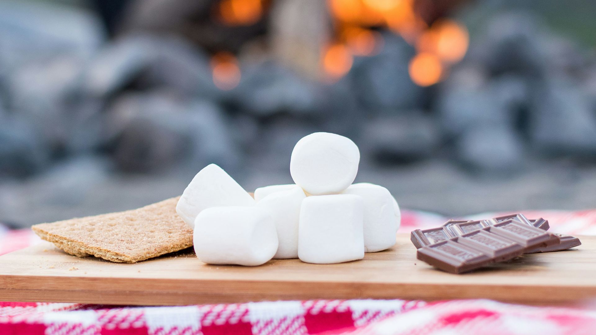 marshmallows and chocolate bar on brown wooden board