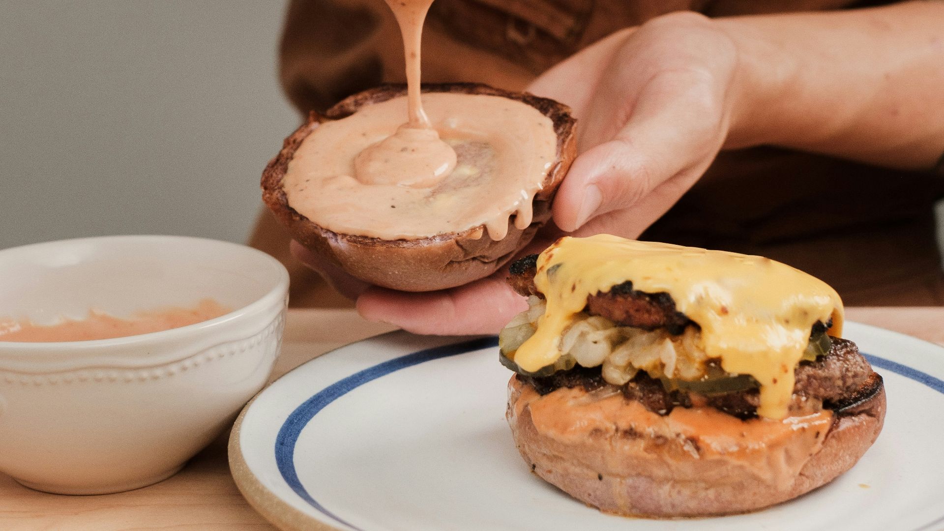 a person is spreading sauce on a hamburger