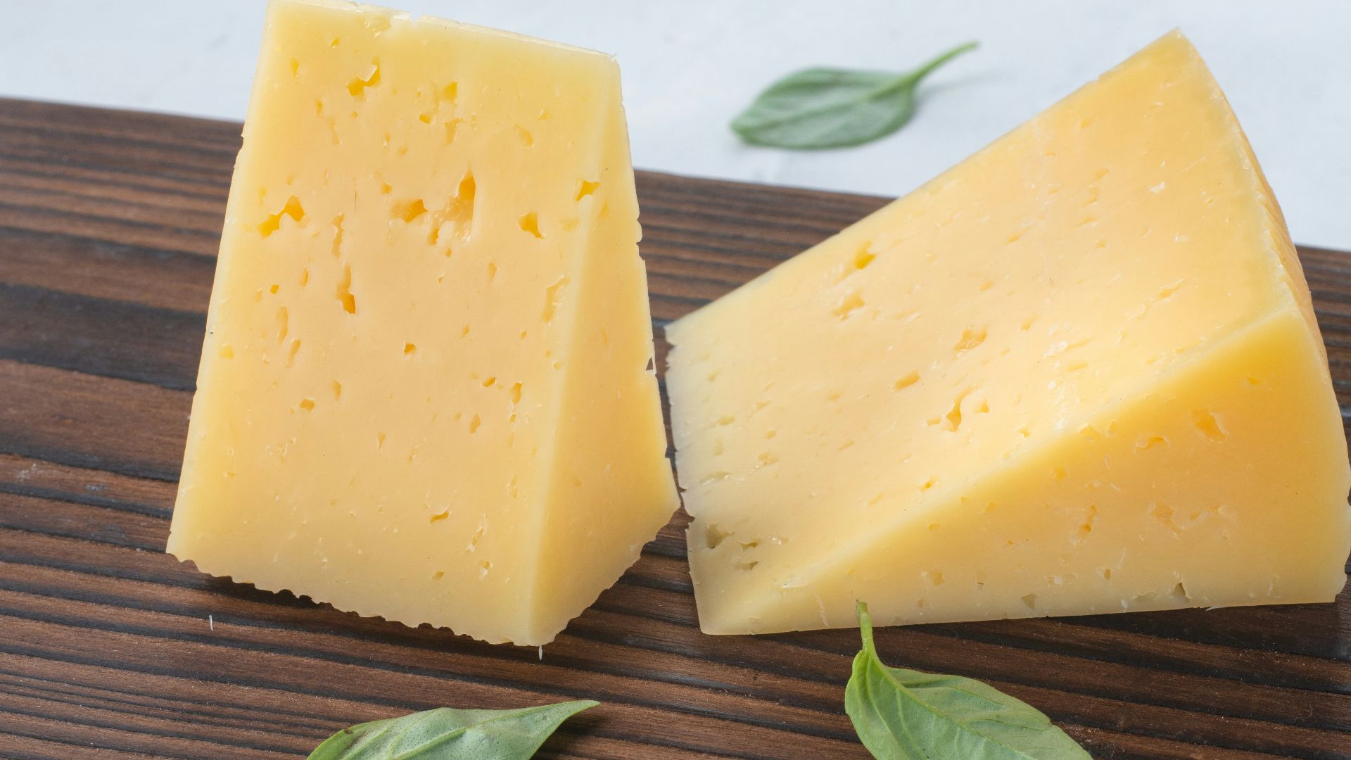 a couple of pieces of cheese sitting on top of a wooden cutting board