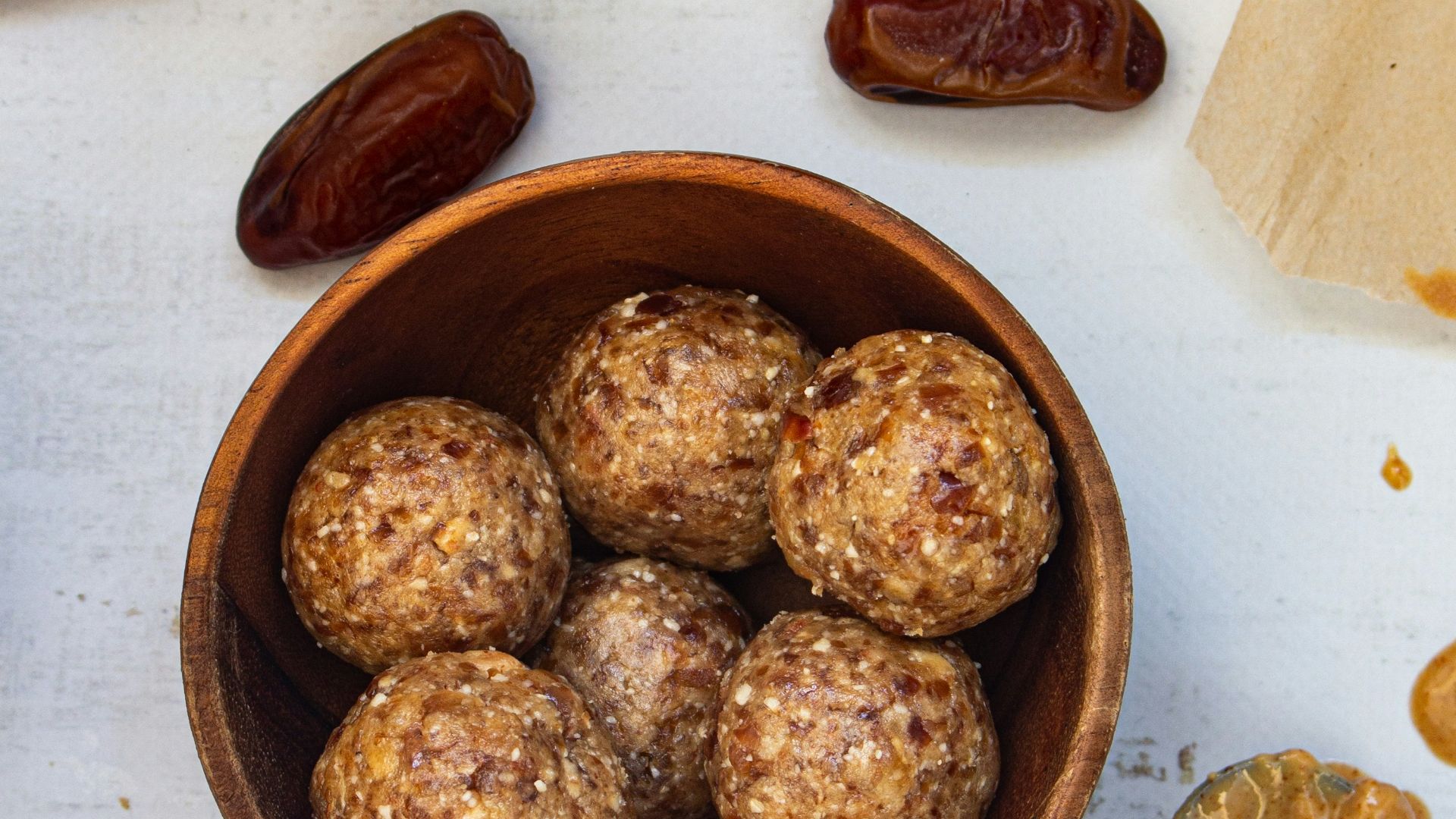 a wooden bowl filled with nuts next to a jar of nuts