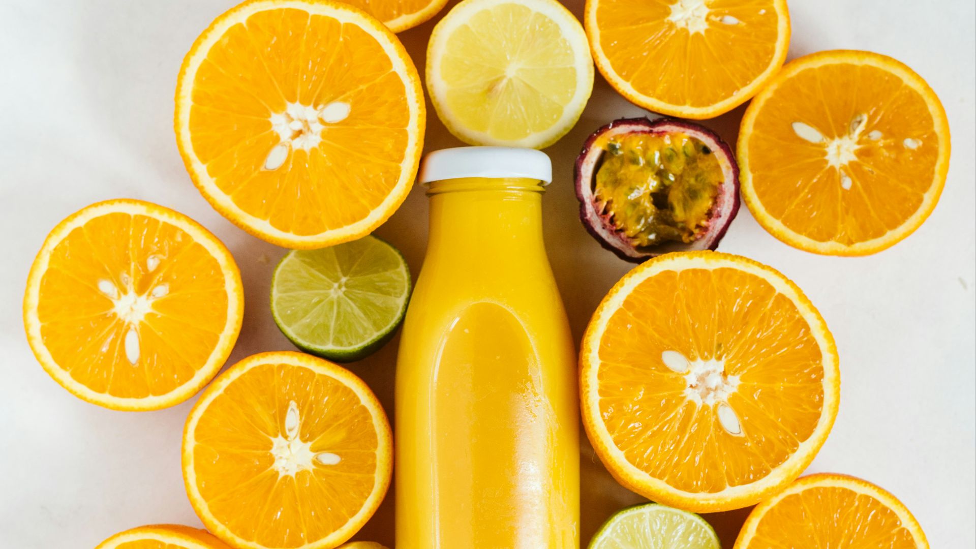 sliced orange fruit beside yellow liquid filled bottle
