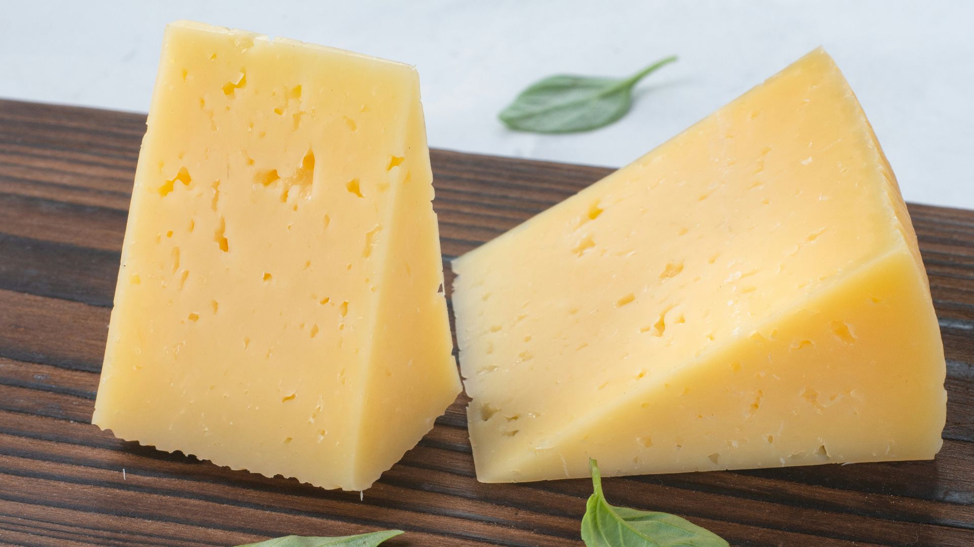 a couple of pieces of cheese sitting on top of a wooden cutting board