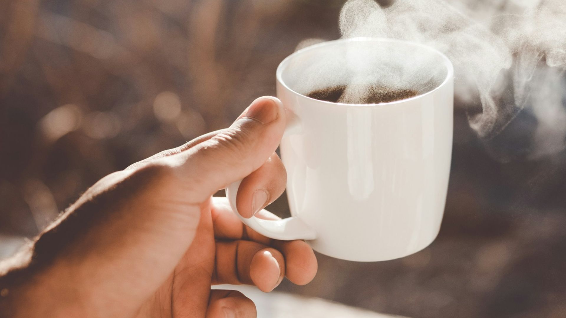 person holding white ceramic cup with hot coffee