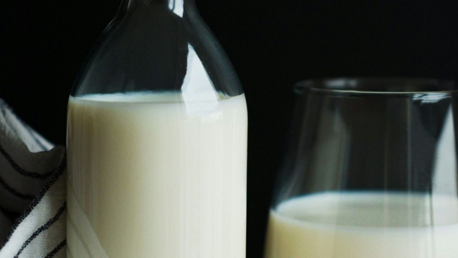 a bottle of milk next to a glass of milk
