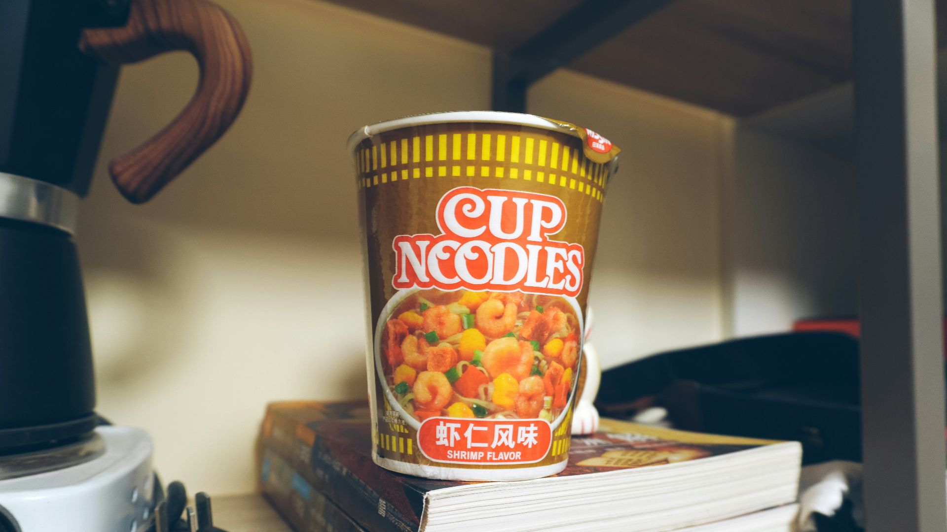 a cup of noodles sitting on top of a stack of books