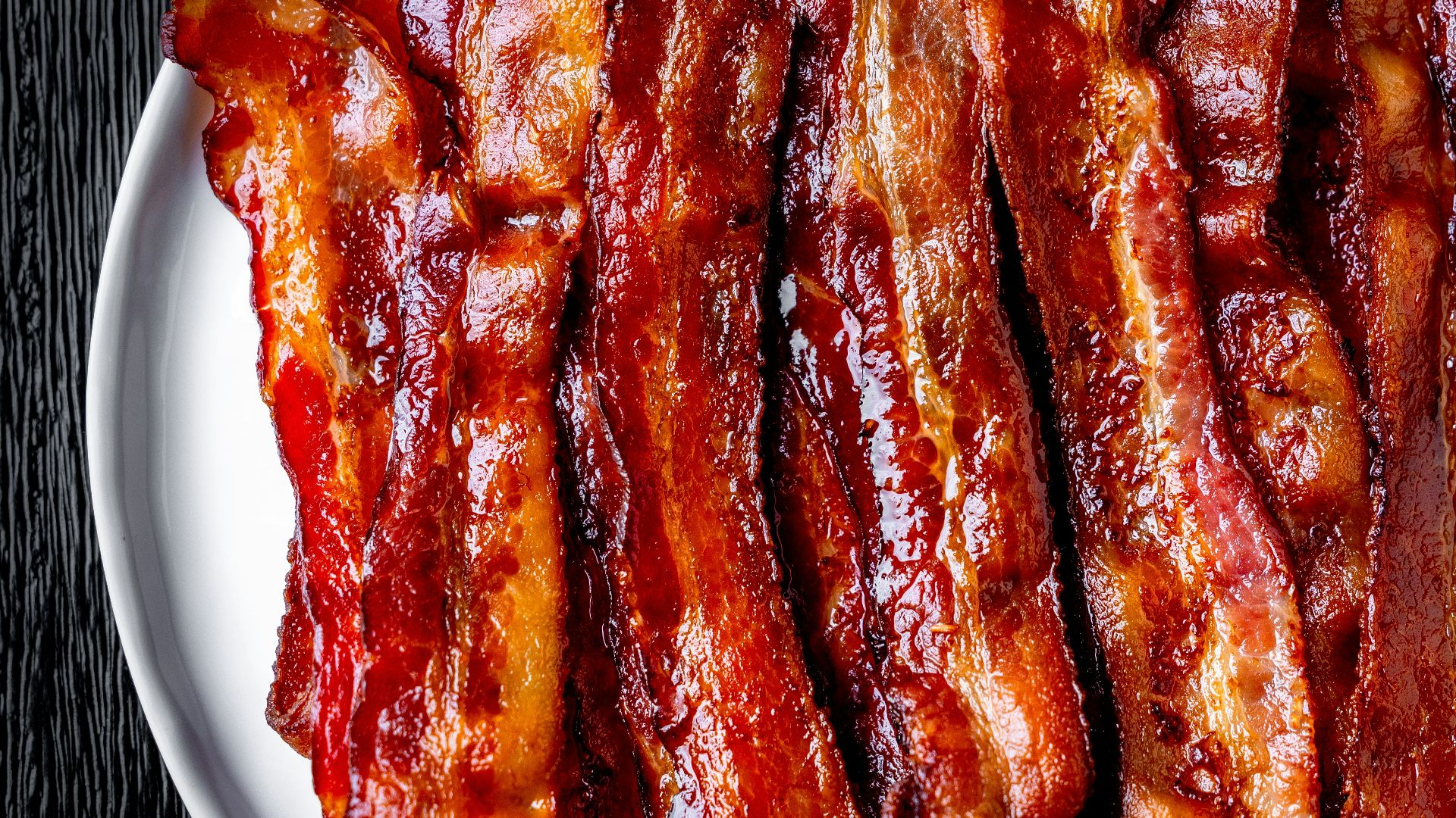 a white plate topped with bacon strips on top of a table