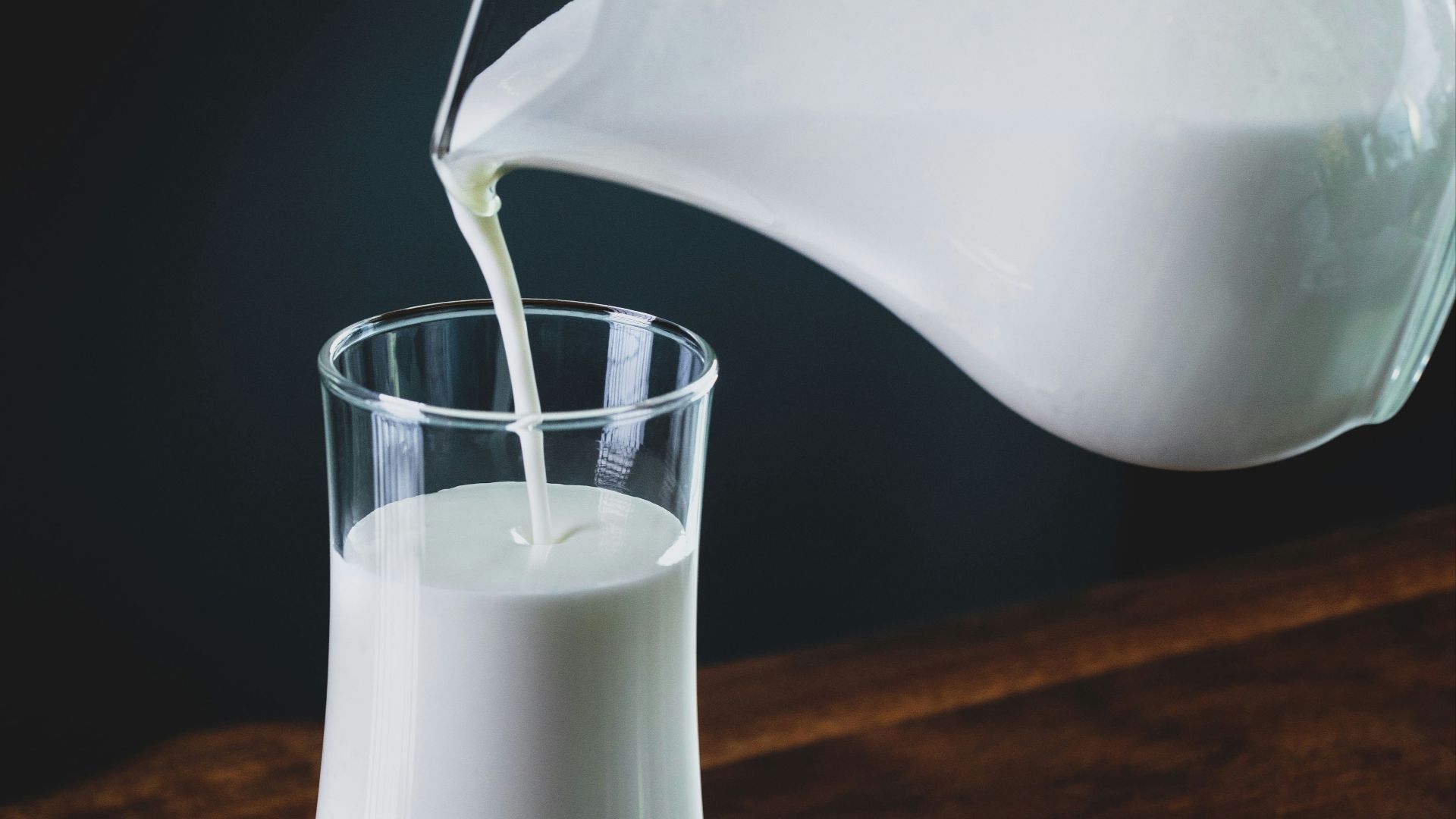 person pours milk into glass