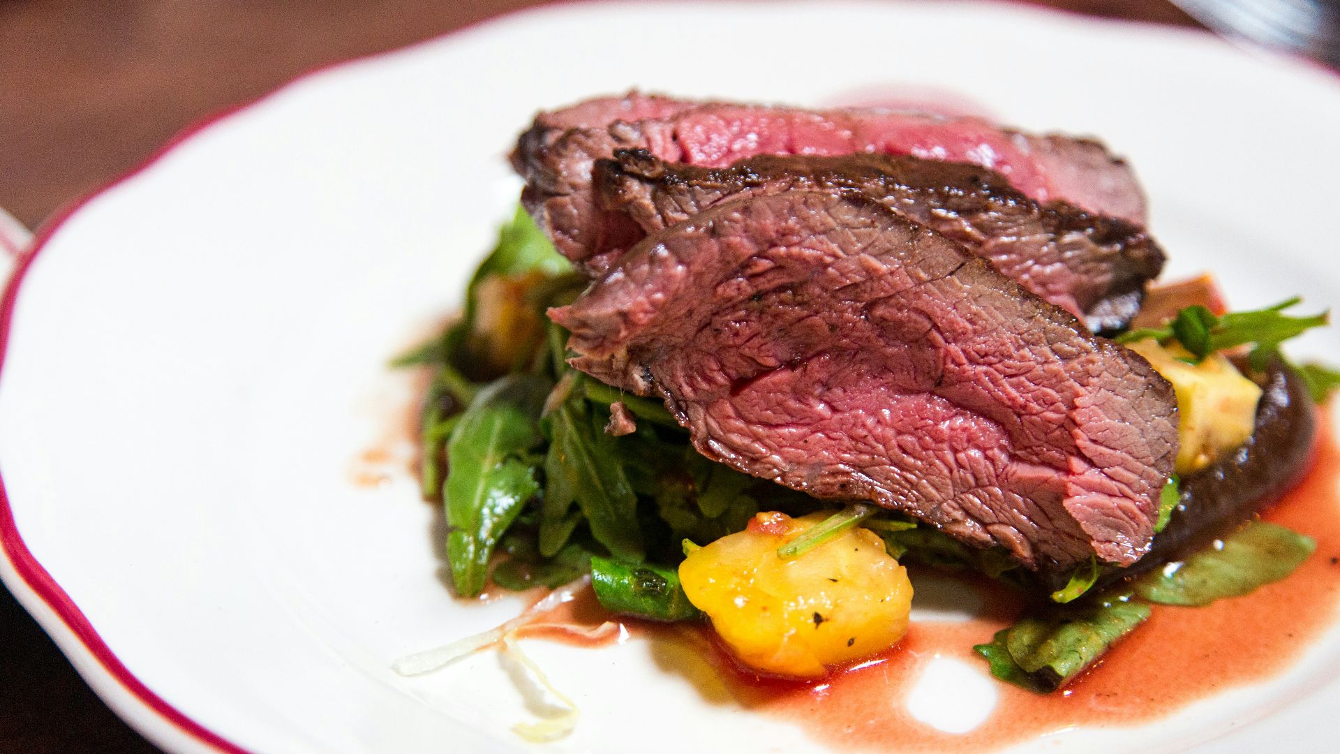 medium rare sliced steak in white ceramic plate