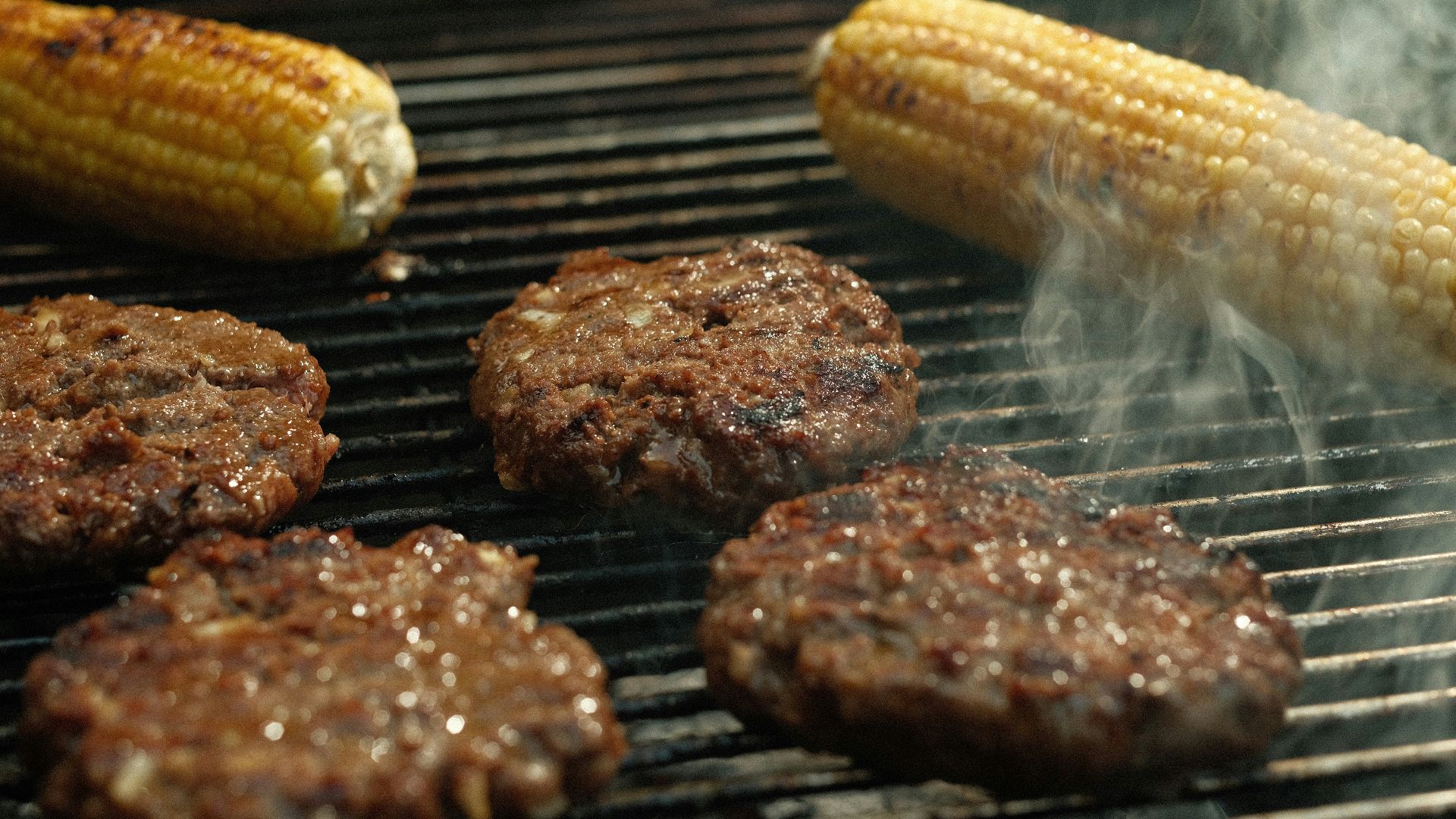 hamburgers and hamburger patties cooking on a grill