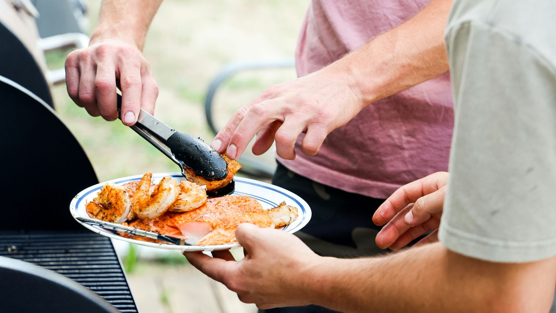 a couple of men standing over a plate of food