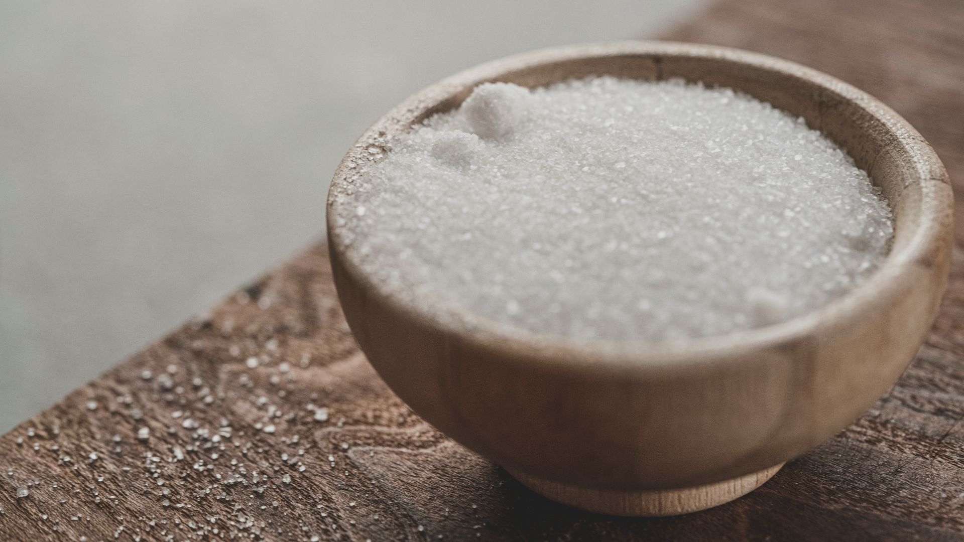 a wooden bowl filled with sugar on top of a wooden table