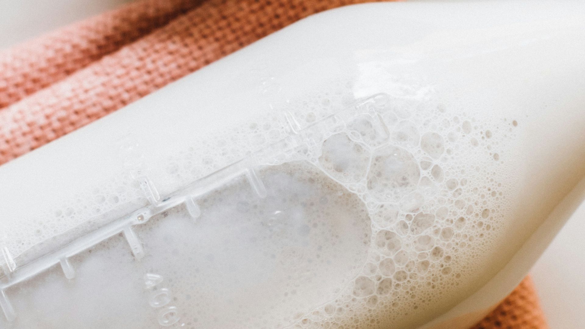 closeup photo of milk bottle beside slice strawberries in white bowl