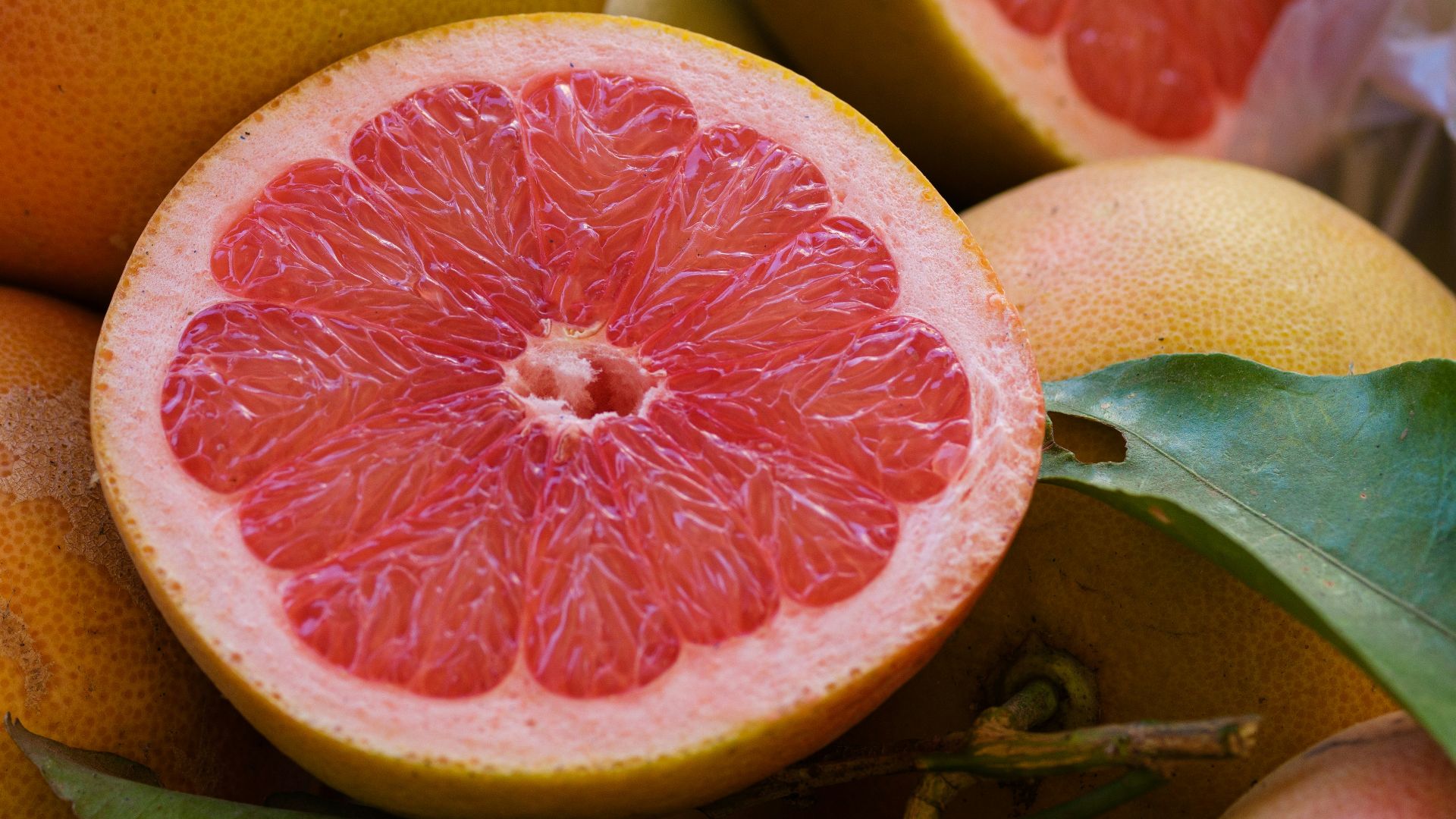 a pile of grapefruits with one cut in half