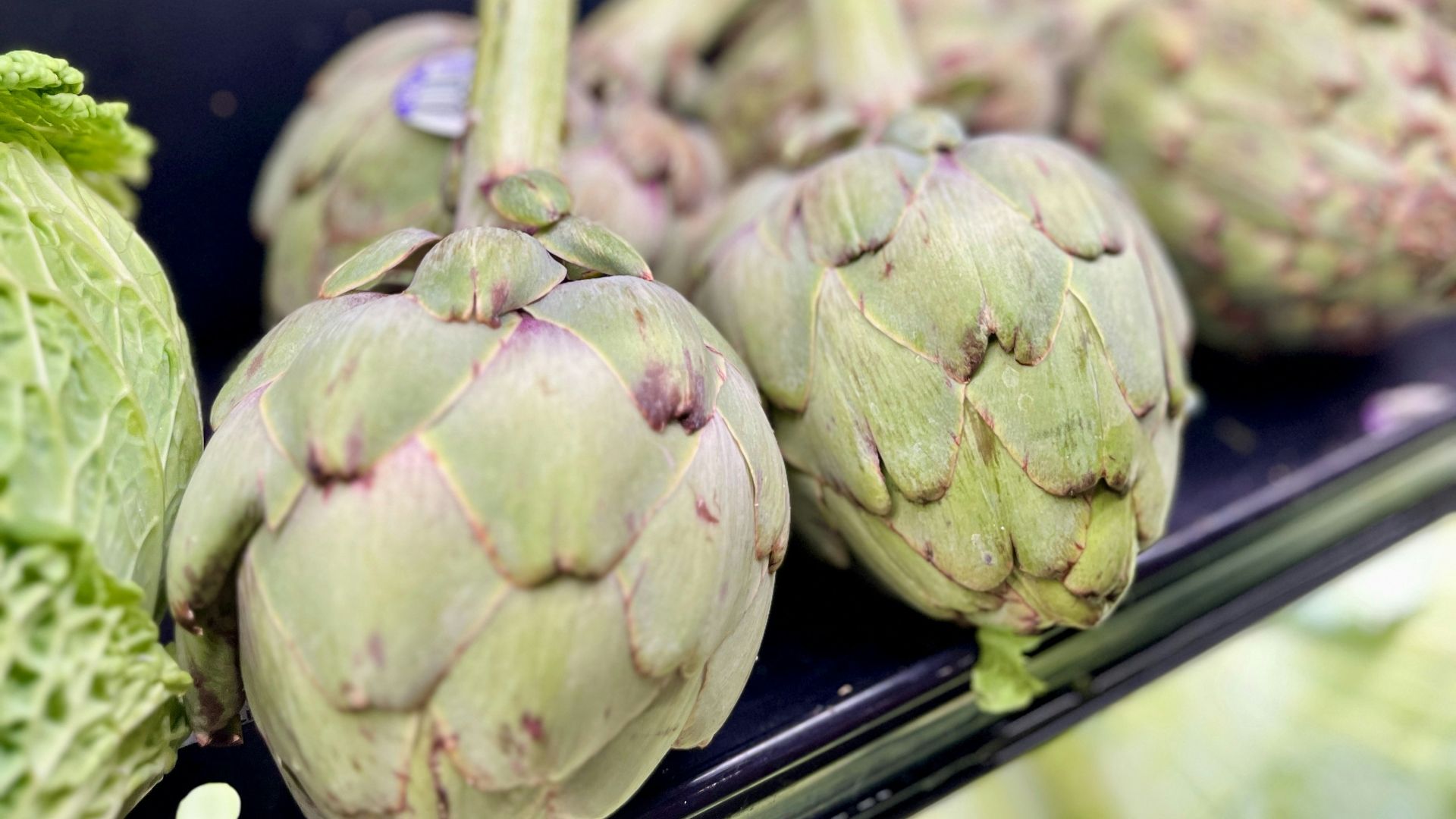 A bunch of artichokes sitting on a shelf in a store