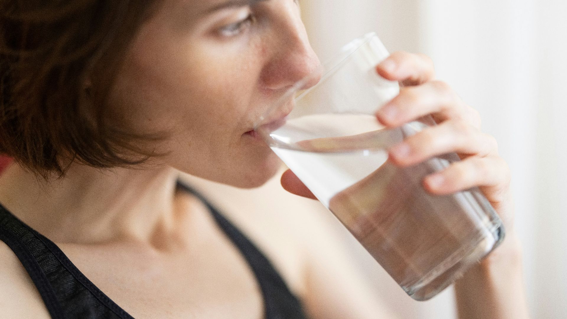 woman in black tank top drinking water