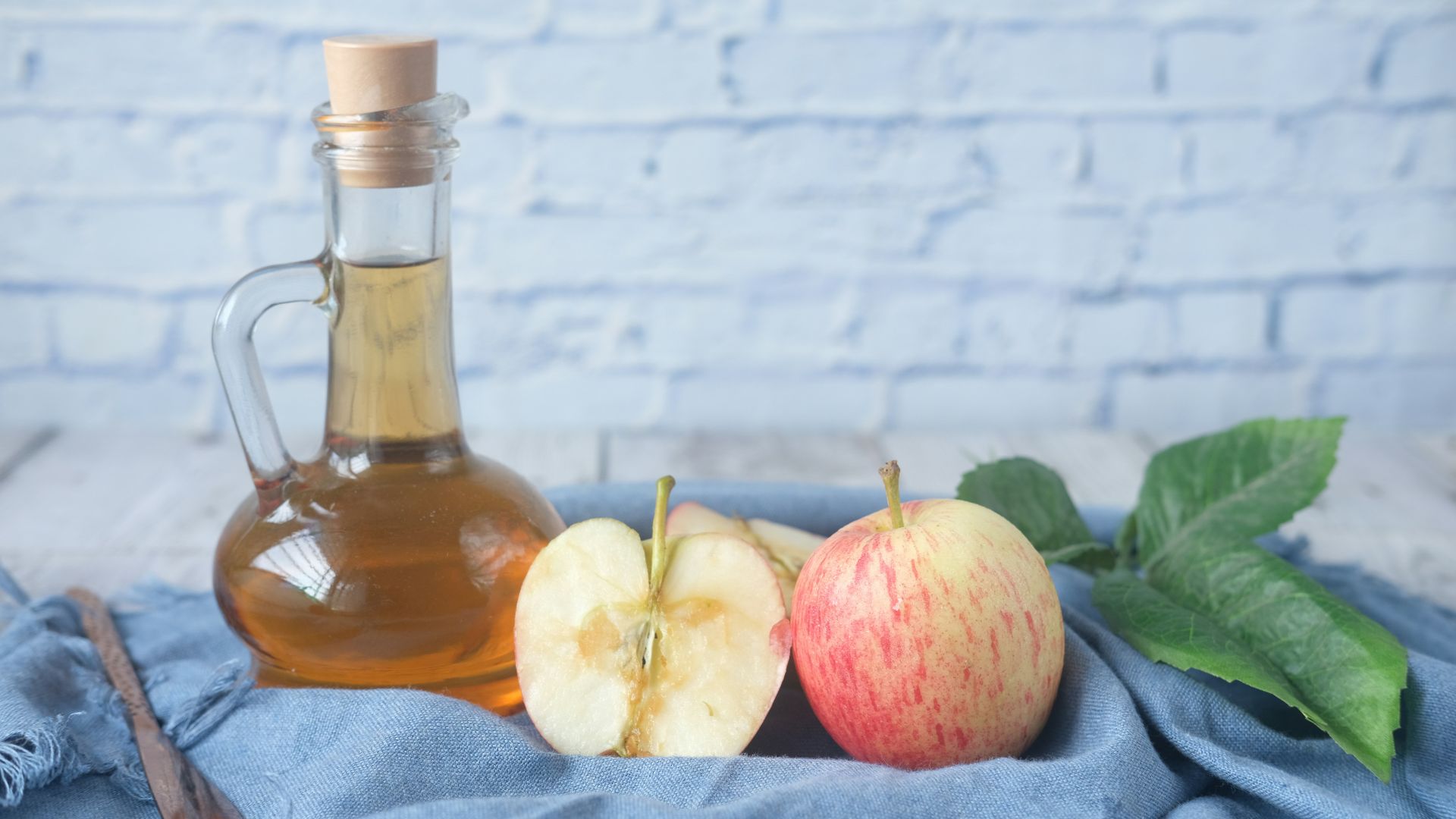 clear glass bottle with red liquid beside sliced lemon on blue textile