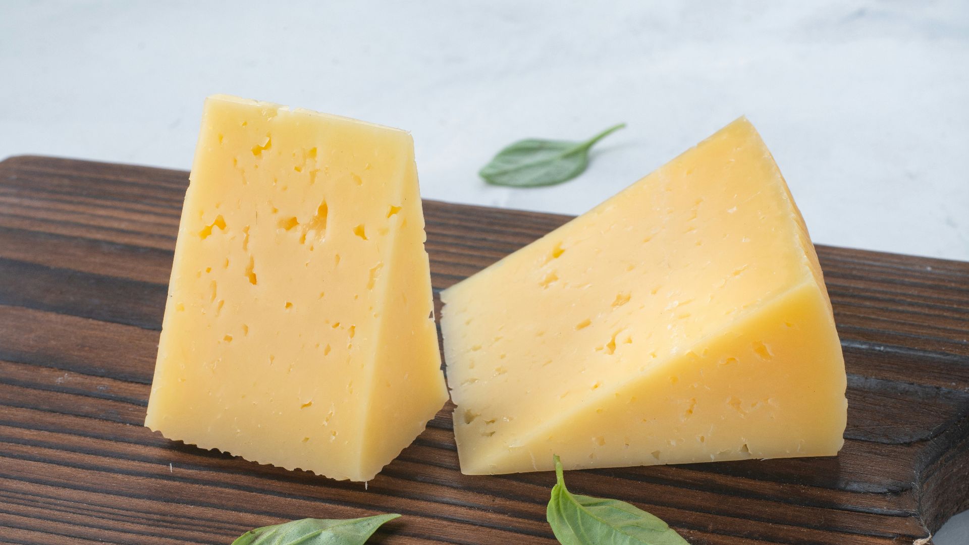 a couple of pieces of cheese sitting on top of a wooden cutting board