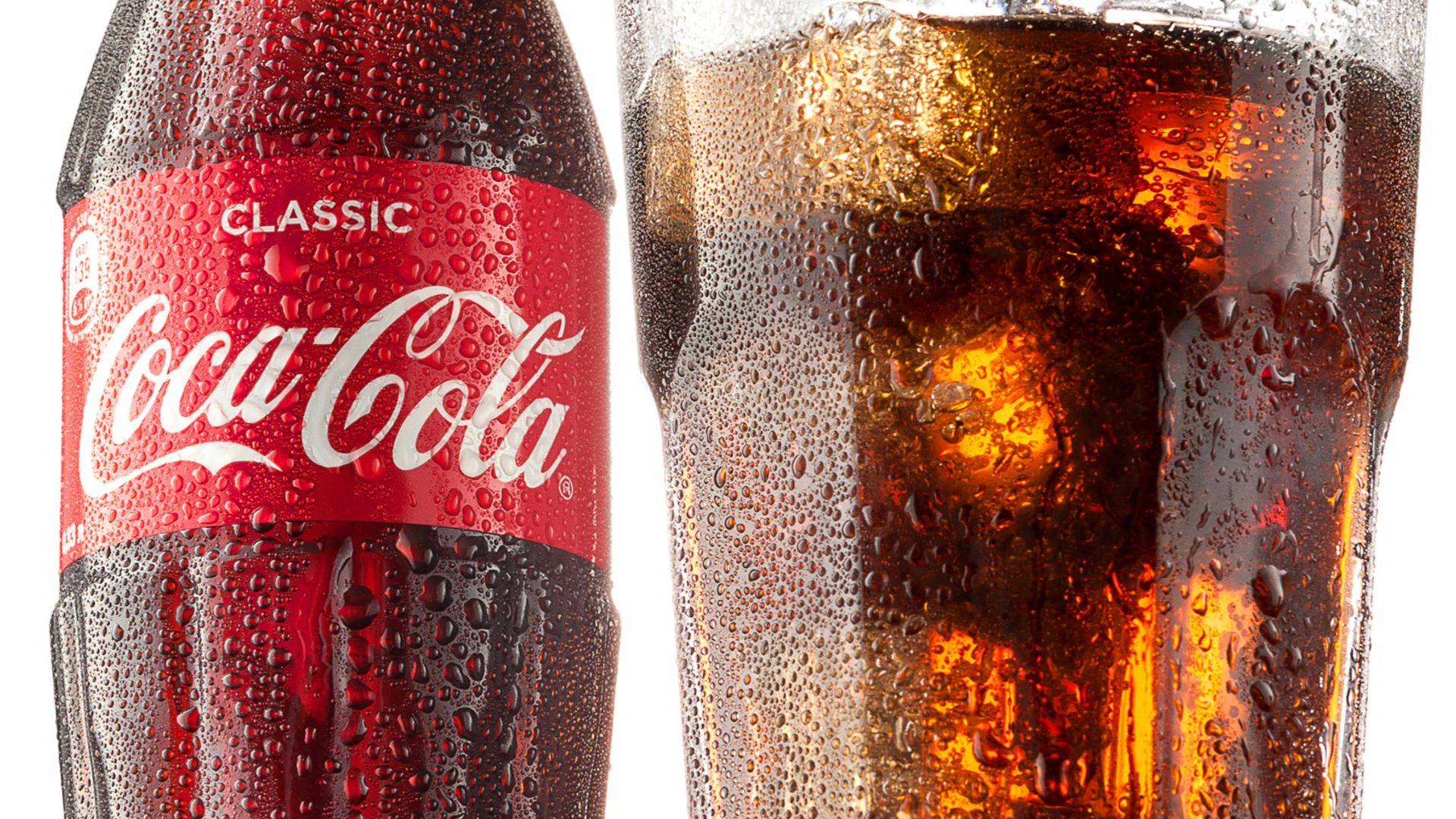 coca cola bottle beside drinking glass